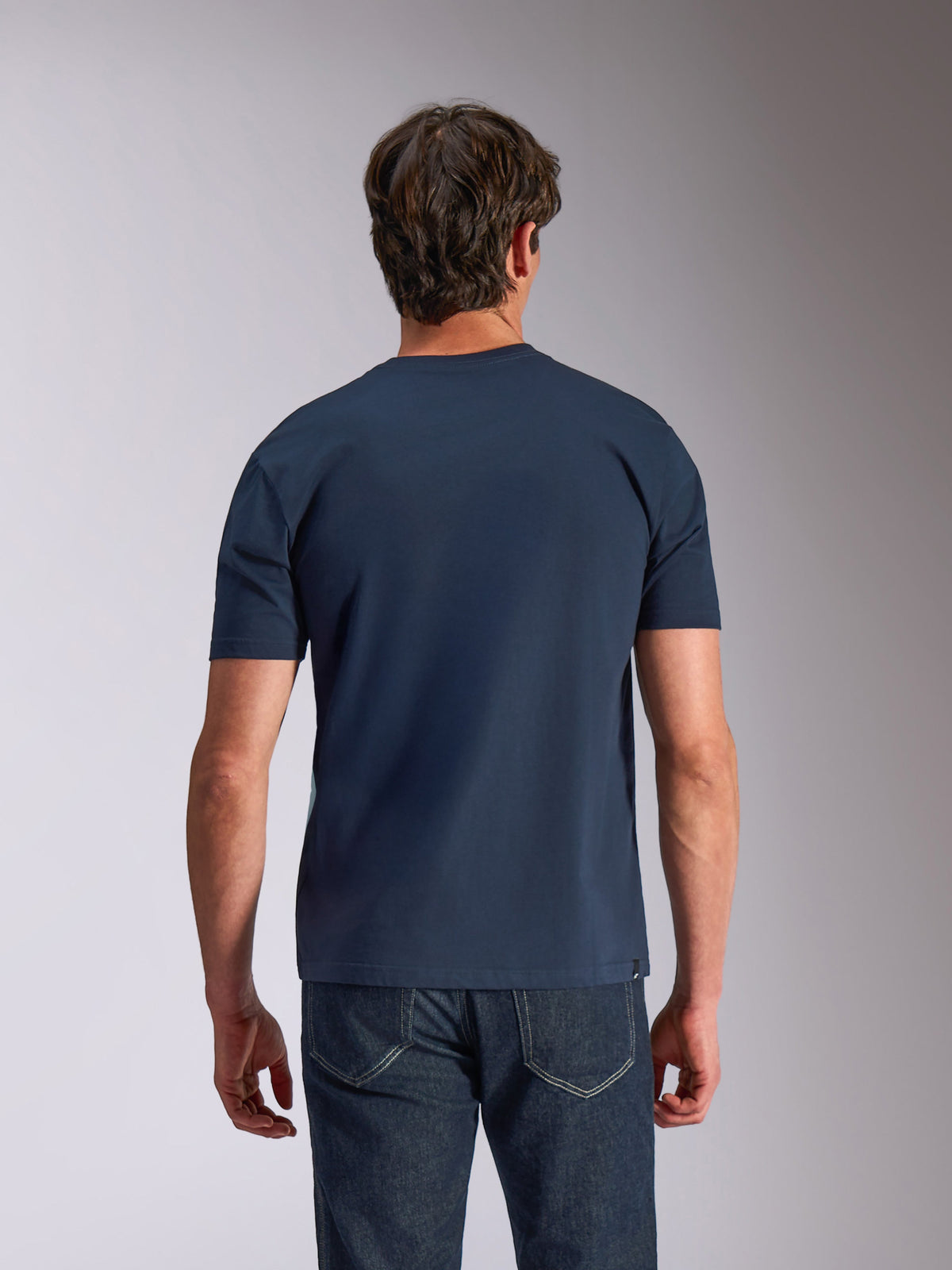 Alpinestars Ageless Shadow CSF Tee, Kurzarm-T-Shirt, Marineblau, Rückansicht, getragen von einem Model mit dunkler Jeans, lässige Motorsport-Lifestyle-Bekleidung
