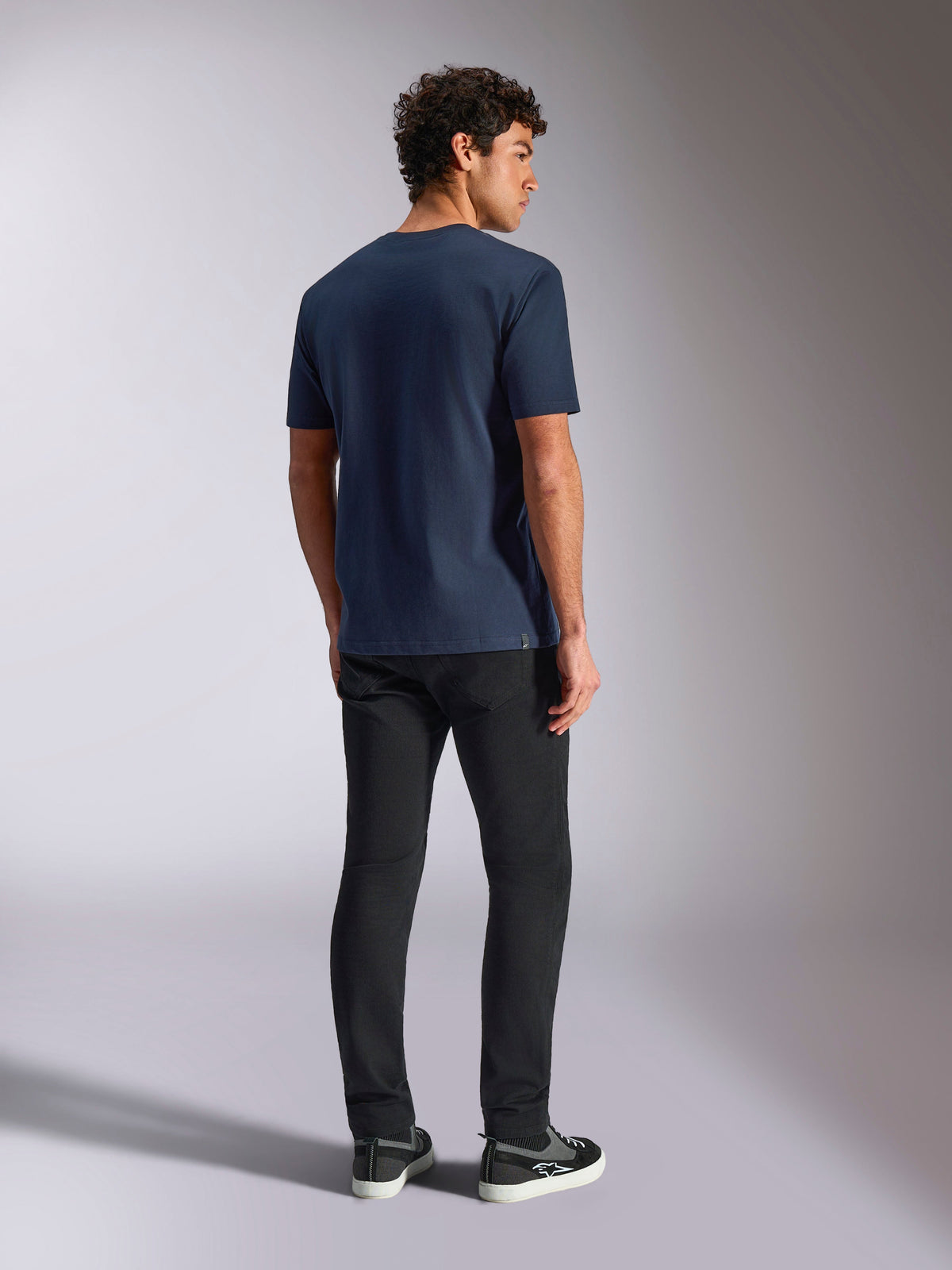 Alpinestars MX Helmet CSF Tee, Kurzarm-T-Shirt, Navy, Rückansicht am Modell, lässige vom Motorsport inspirierte Sportbekleidung, getragen mit schwarzer Hose und Sneakern