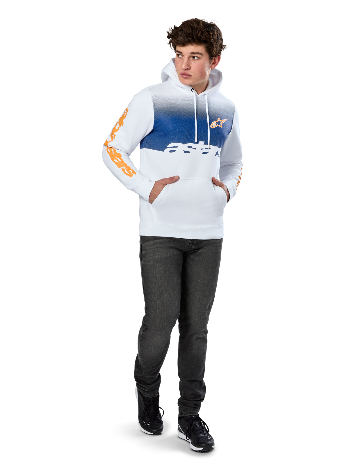Alpinestars Specter Hoodie, weißer Fleece-Hoodie mit blauem Farbverlauf-Druck, orangefarbenes HD-Frontlogo und Wortmarken auf den Ärmeln, Kängurutasche und Kapuze mit Kordelzug, kombiniert mit dunklen Jeans für einen lässigen, vom Motorsport inspirierten Look