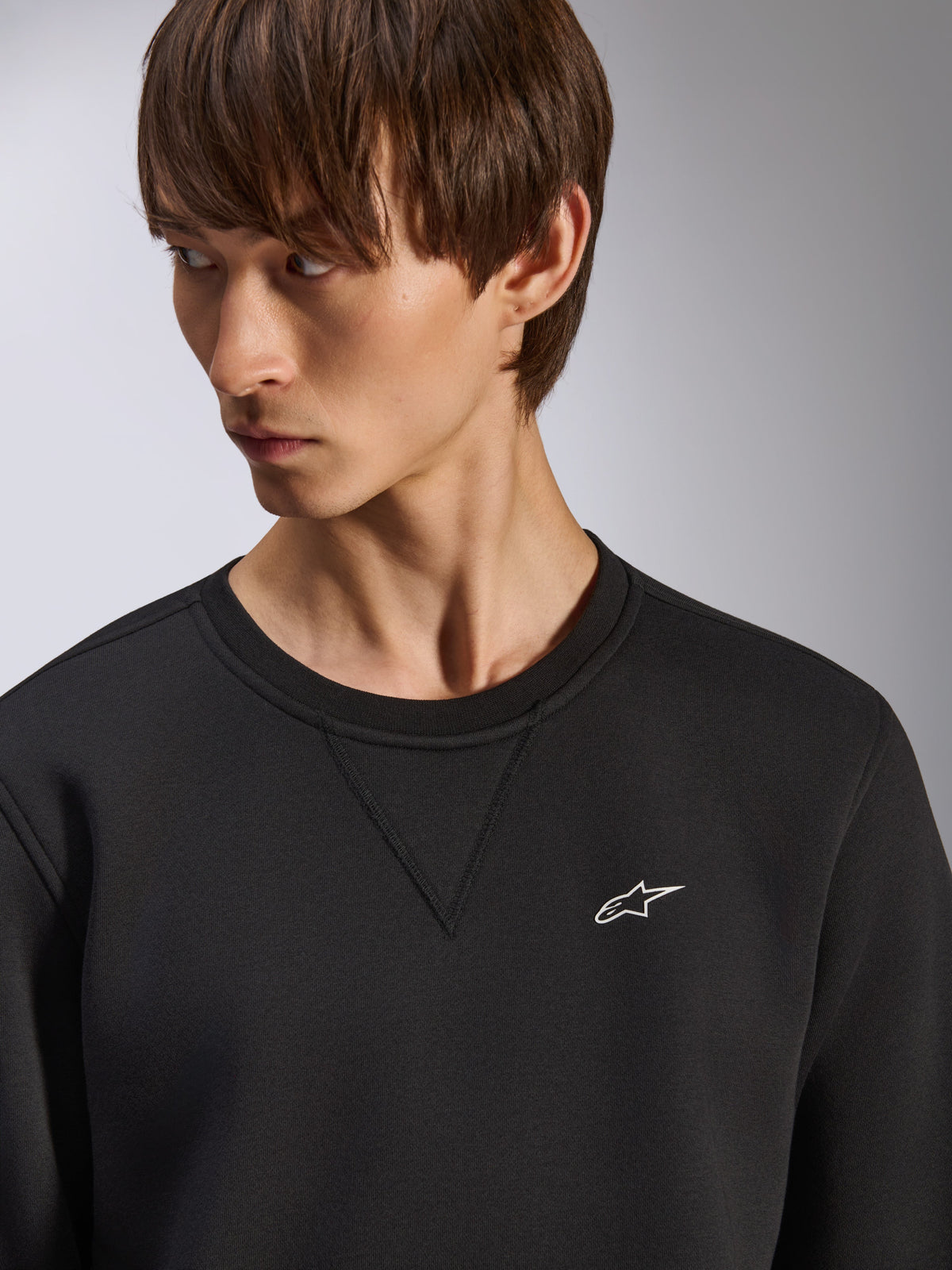Alpinestars Positive Crew sweatshirt, black crewneck with V-stitch detail at the neck, small white Alpinestars logo on the left chest, casual motorsport-inspired streetwear