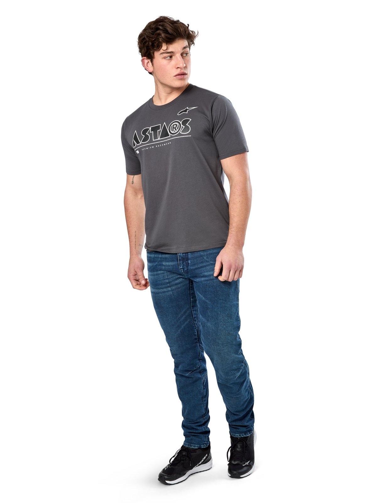 Alpinestars Cereal CSF Tee, Kurzarm-T-Shirt, Anthrazit, weißes geometrisches Astars-Textlogo, lässige Motorsport-Streetwear, kombiniert mit blauen Jeans und schwarzen Sneakern