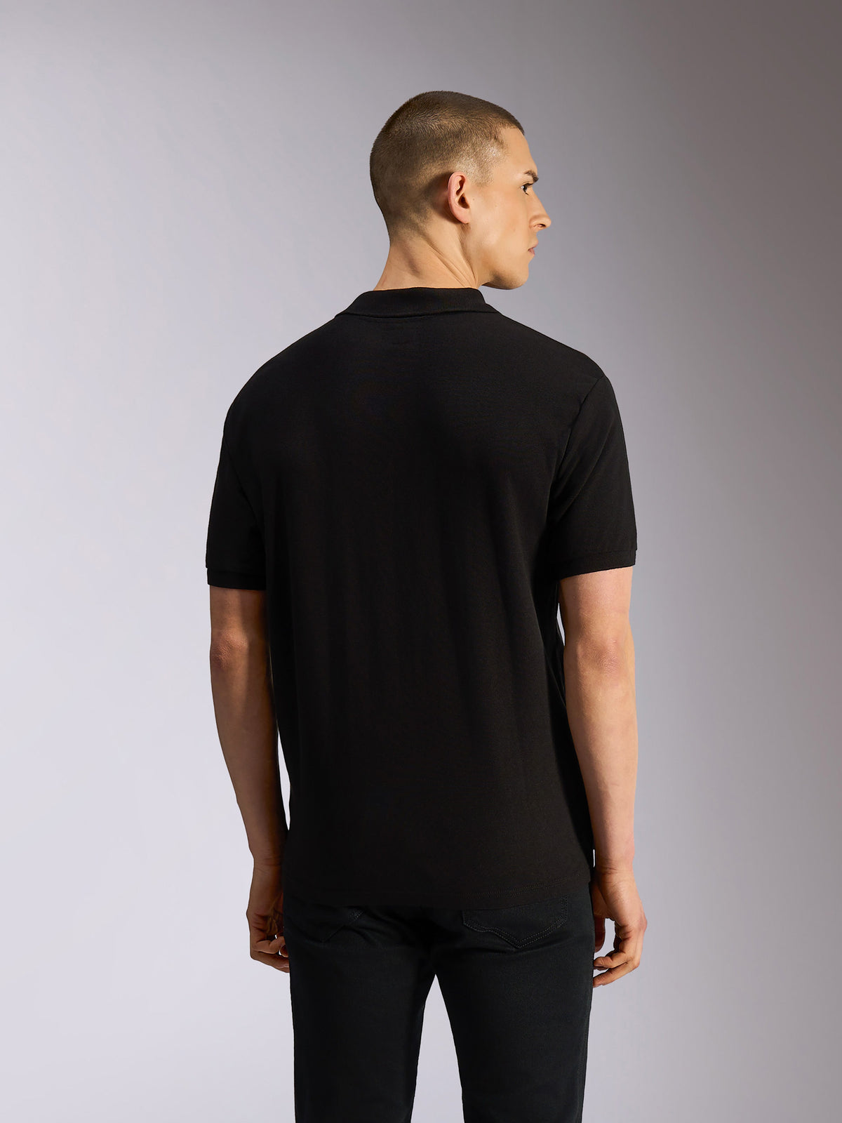 Alpinestars Endeavor Classic Polo, Kurzarm-Poloshirt, Schwarz, Rückansicht am Model, klassisches Piqué-Gewebe mit Rippkragen und Ärmelbündchen, lässige, vom Motorsport inspirierte Bekleidung