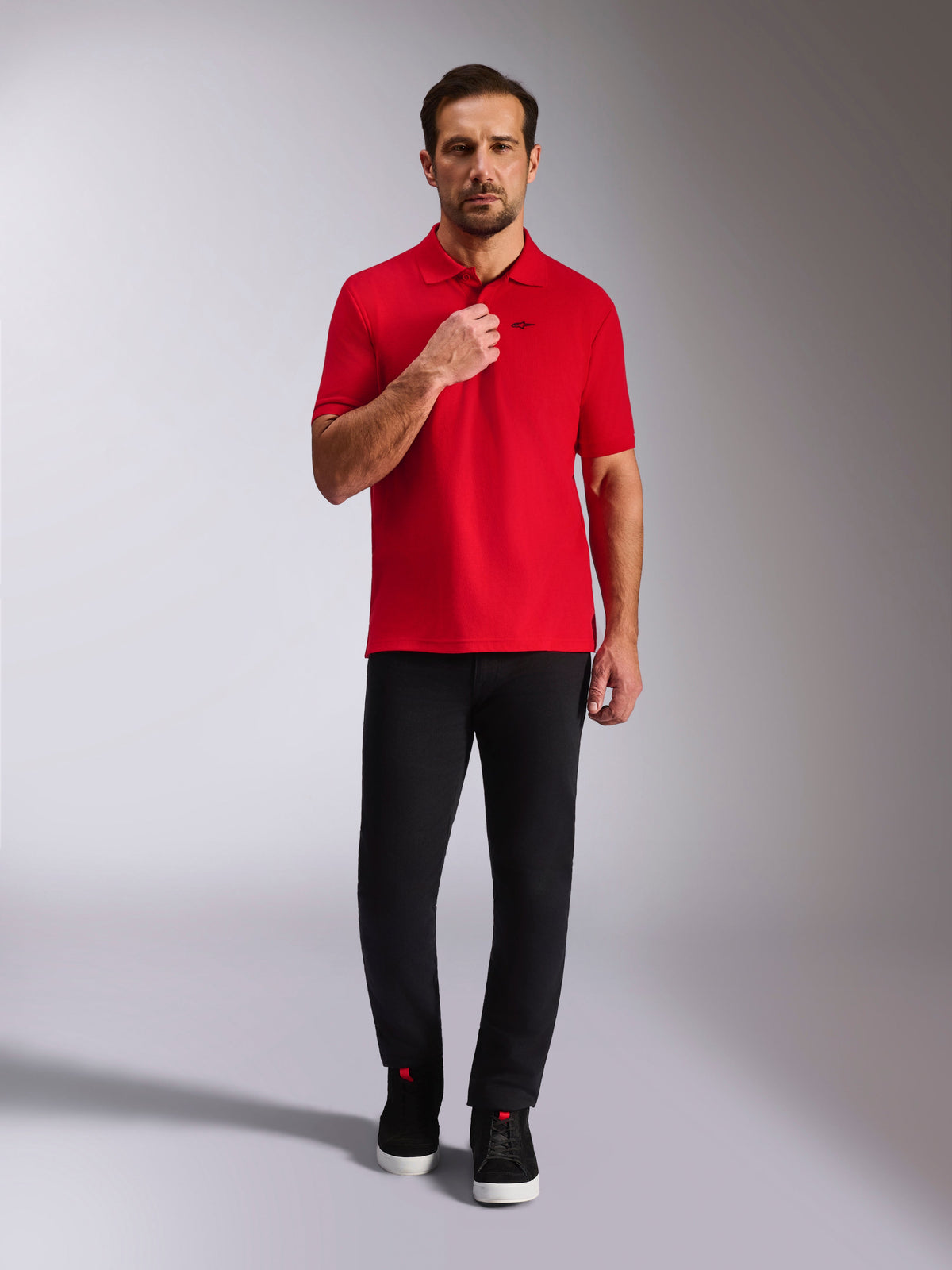 Alpinestars Endeavor Classic Polo, Red Pique Polo Shirt, Short Sleeve with black Astars logo, ribbed collar and sleeve cuffs, worn with black pants and sneakers, casual motorsport-inspired streetwear
