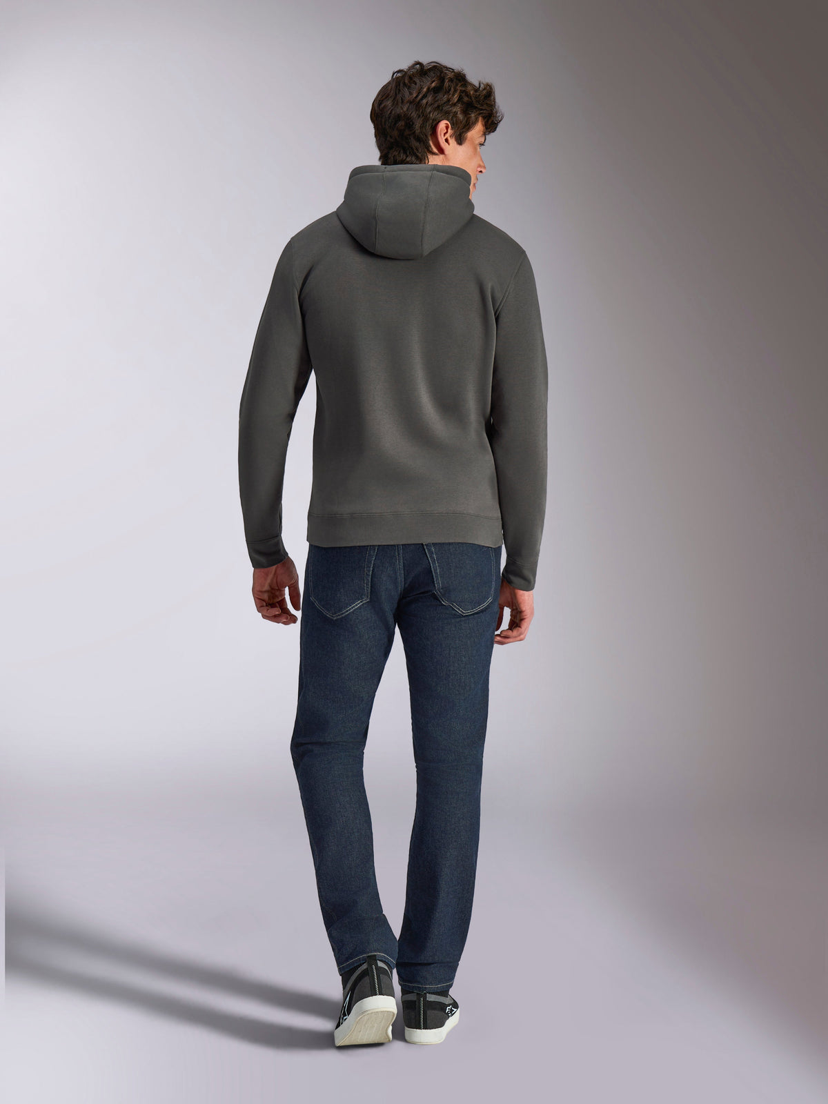 Alpinestars Ellipsoid Hoodie, gunmetal-grauer Kapuzenpullover, Rückansicht, getragen von einem Model mit dunkler Denim-Jeans und schwarzen Sneakern, lässige, vom Motorsport inspirierte Streetwear