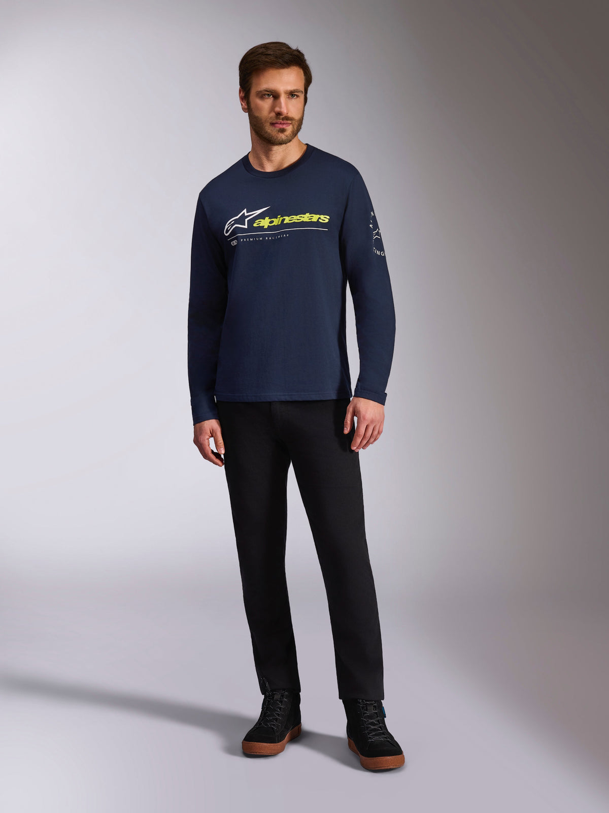 Alpinestars Mandatory CSF Langarmshirt, Marineblau, weißes Astars-Logo mit neongelbem Schriftzug, getragen von einem Model mit schwarzer Hose und schwarzen Sneakern, lässige Motorsport-Streetwear