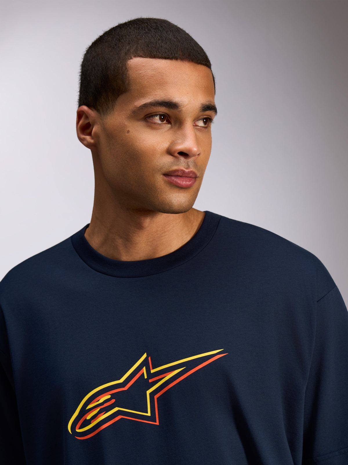 Alpinestars Alter Oversized CSF T-Shirt, kurzärmeliges T-Shirt, Navy, Astars-Logo mit gelbem und orangem Farbversatz-Druck, lässiger Streetwear-Stil, getragen von einem Modell