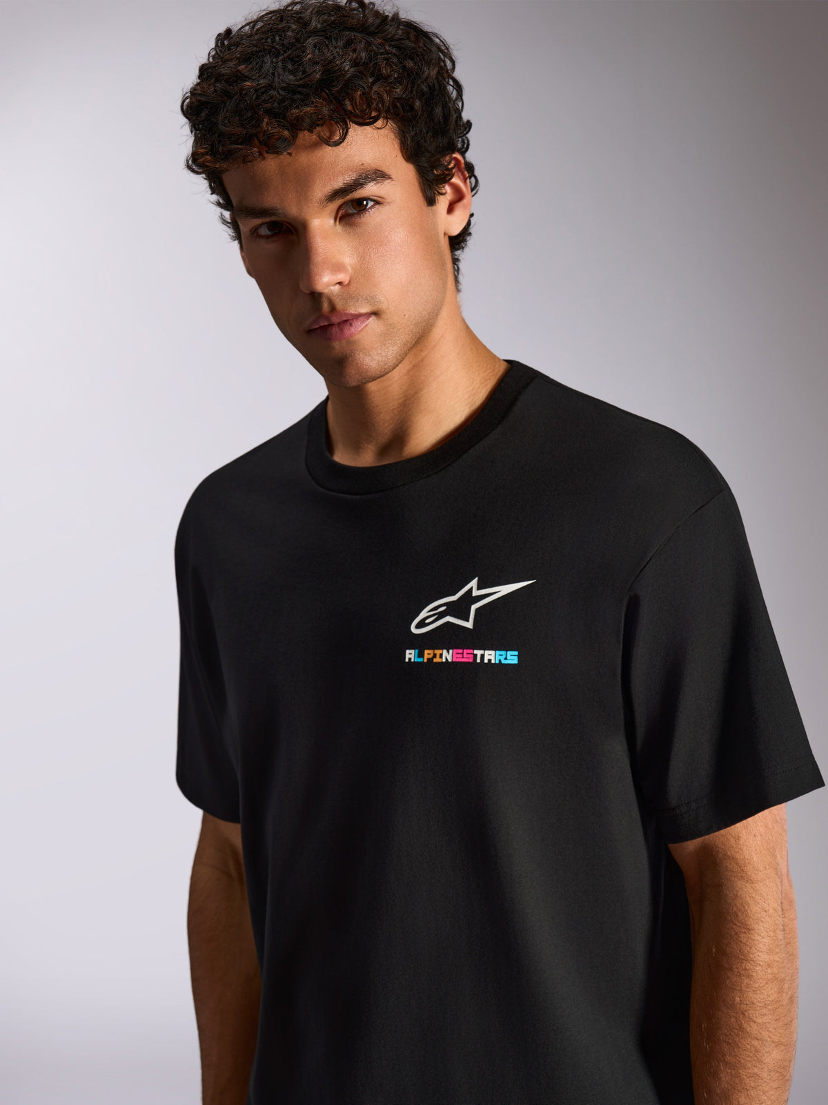 Alpinestars Wild Oversized CSF Tee, schwarzes kurzärmeliges T-Shirt mit weißem Astars-Logo und lebhaftem mehrfarbigem Branding auf der Brust, lässige Motorsport-Streetwear