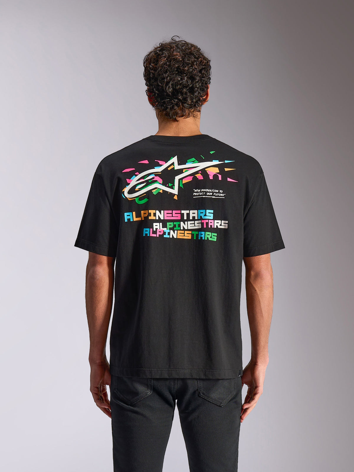 Alpinestars Wild Oversized CSF Tee, Kurzarm-T-Shirt, Schwarz, Rückansicht mit lebendigem mehrfarbigem Astars-Logo und grafischen Elementen, lässige Motorsport-Streetwear