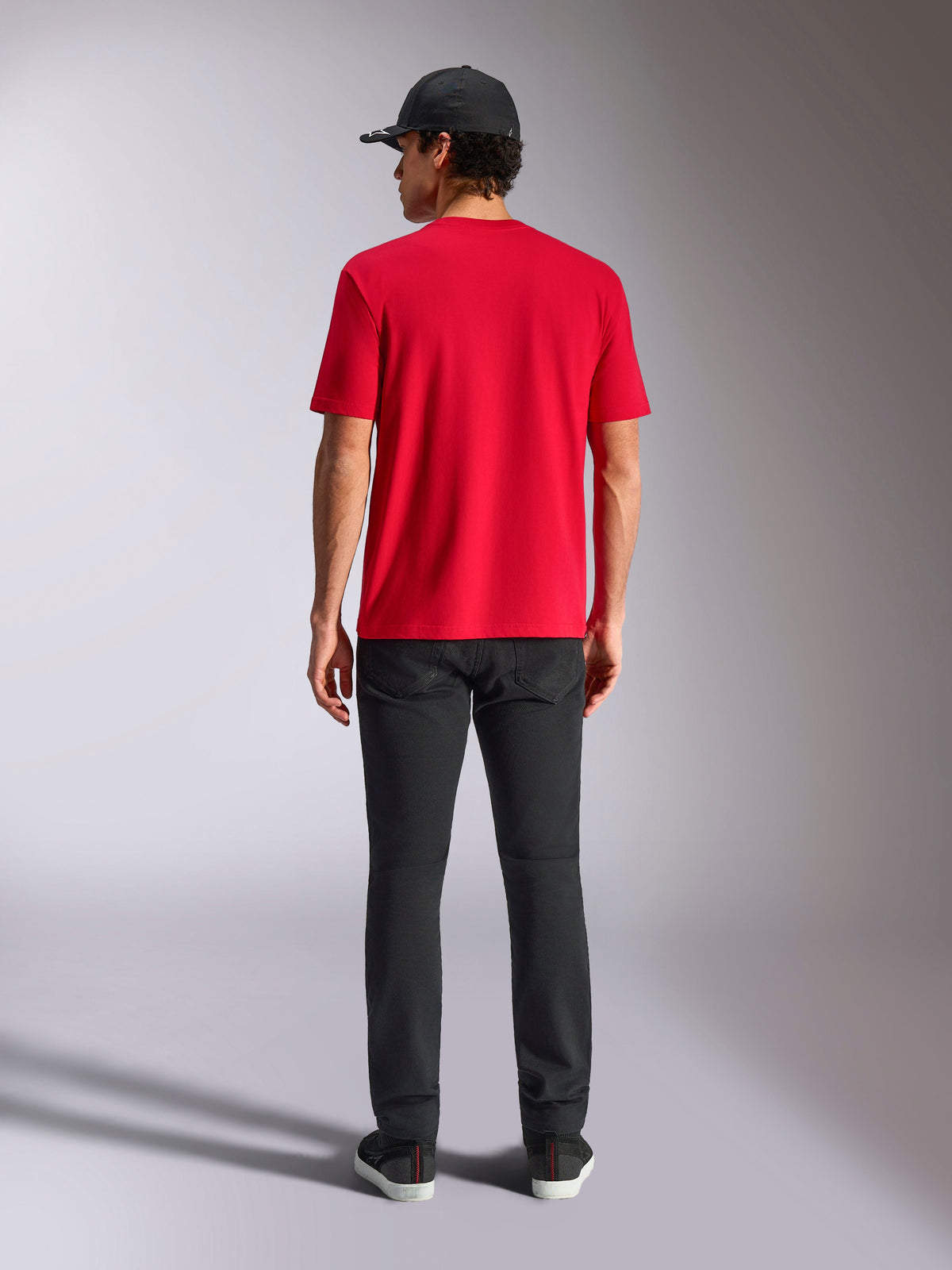 Alpinestars Noka CSF Tee, Kurzarm-T-Shirt, Rot, Rückansicht, kombiniert mit schwarzer Hose und einer schwarzen Baseballkappe, lässige Motorsport-inspirierte Streetwear