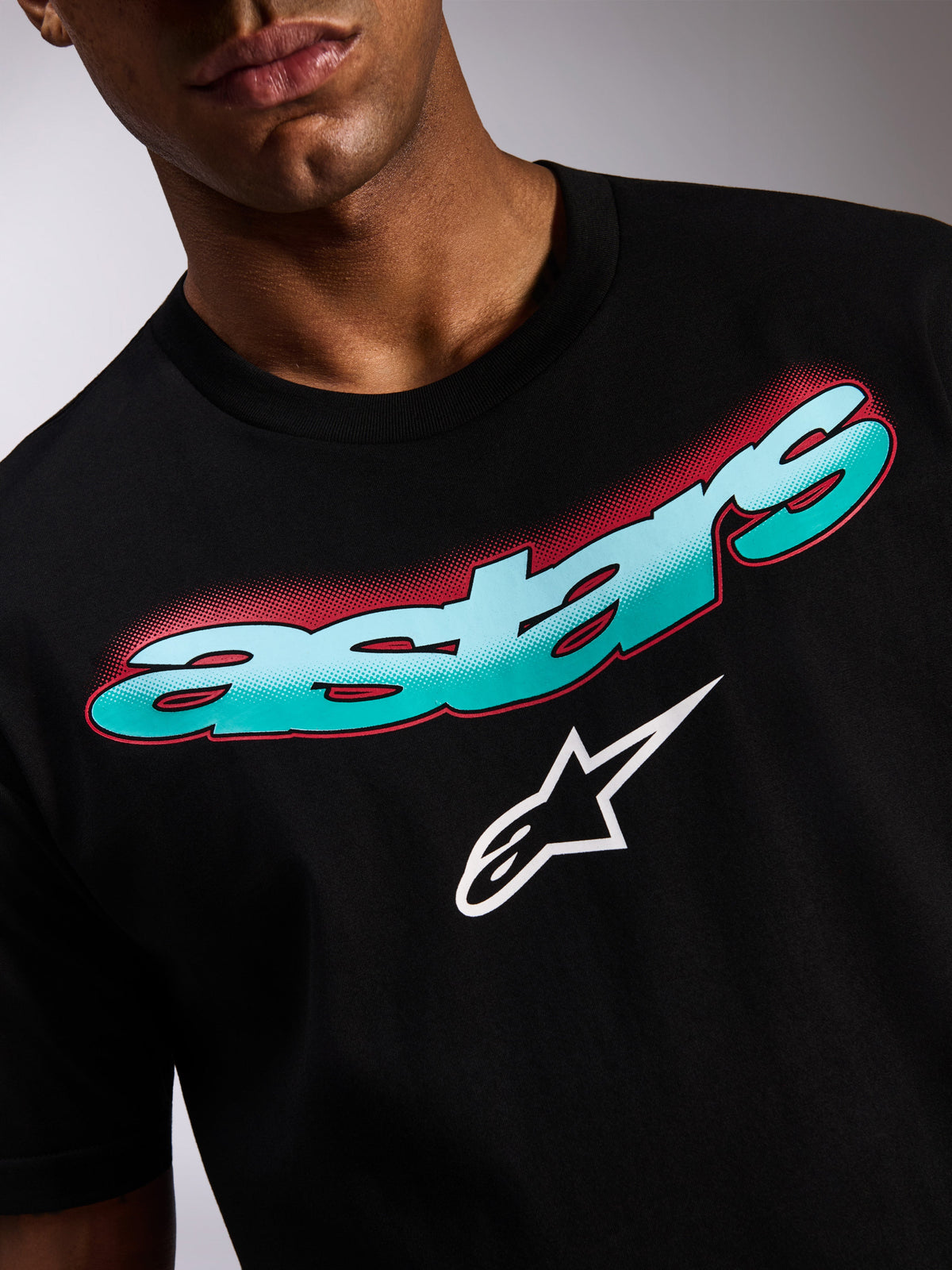 Alpinestars Ellipsoid CSF Tee, Short Sleeve T-Shirt, Black, close-up of front graphic featuring teal and blue gradient Astars wordmark with red halftone shadow and white star logo, casual motorsport streetwear