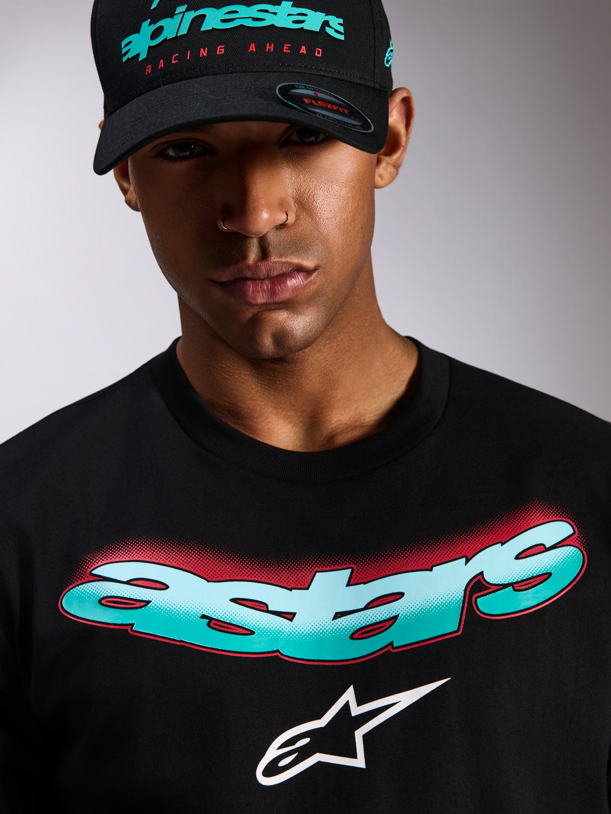 Alpinestars Ellipsoid CSF Tee, Short Sleeve T-Shirt, Black, Teal and White Gradient Astars Wordmark with Red Halftone Detail, White Astars Logo, worn with matching black Alpinestars cap, Casual Motorsport Streetwear