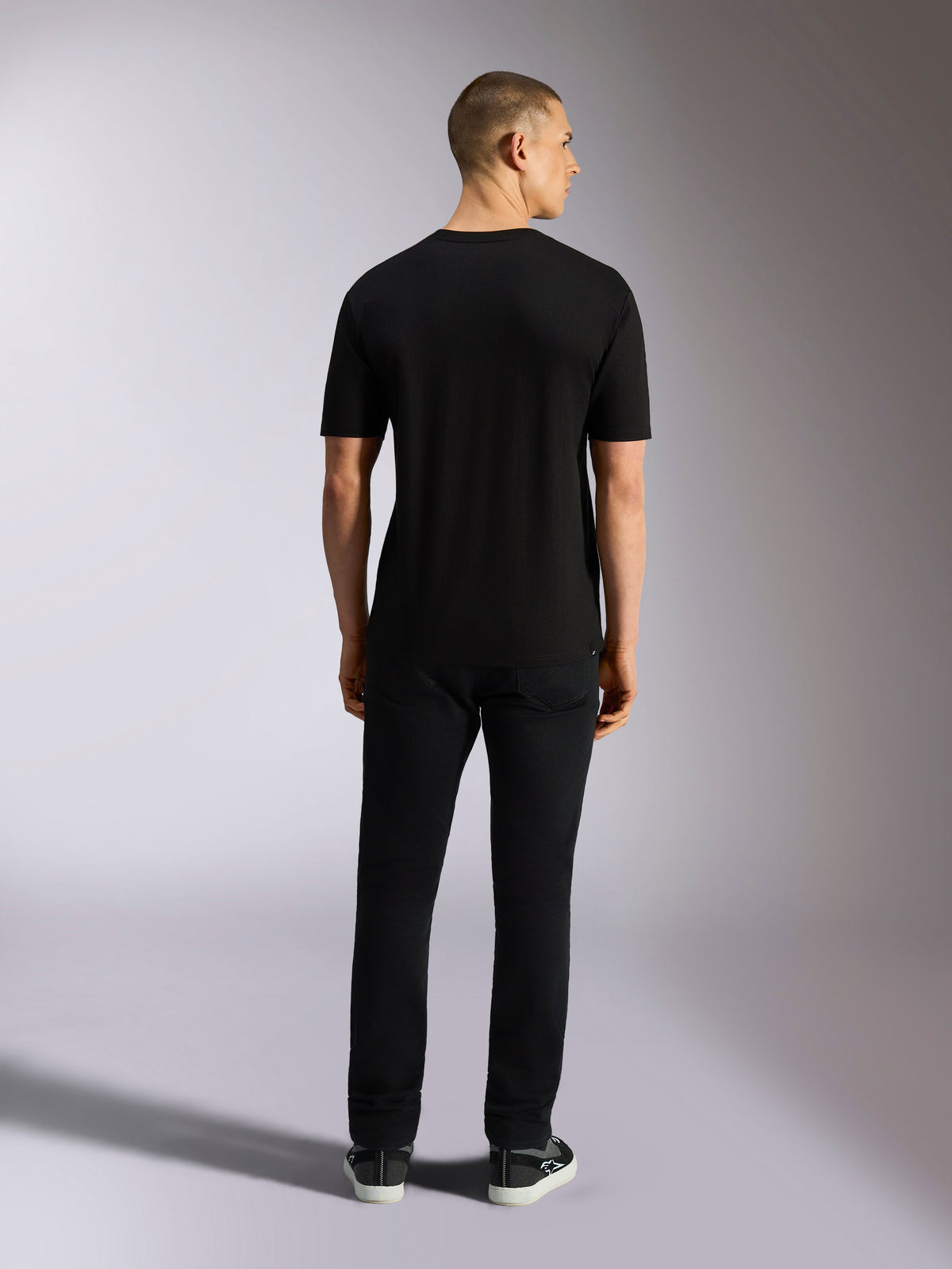 Alpinestars MX CSF Tee, Kurzarm-T-Shirt, Schwarz, Rückansicht eines Models in schwarzer Hose, lässige, vom Motorsport inspirierte Bekleidung
