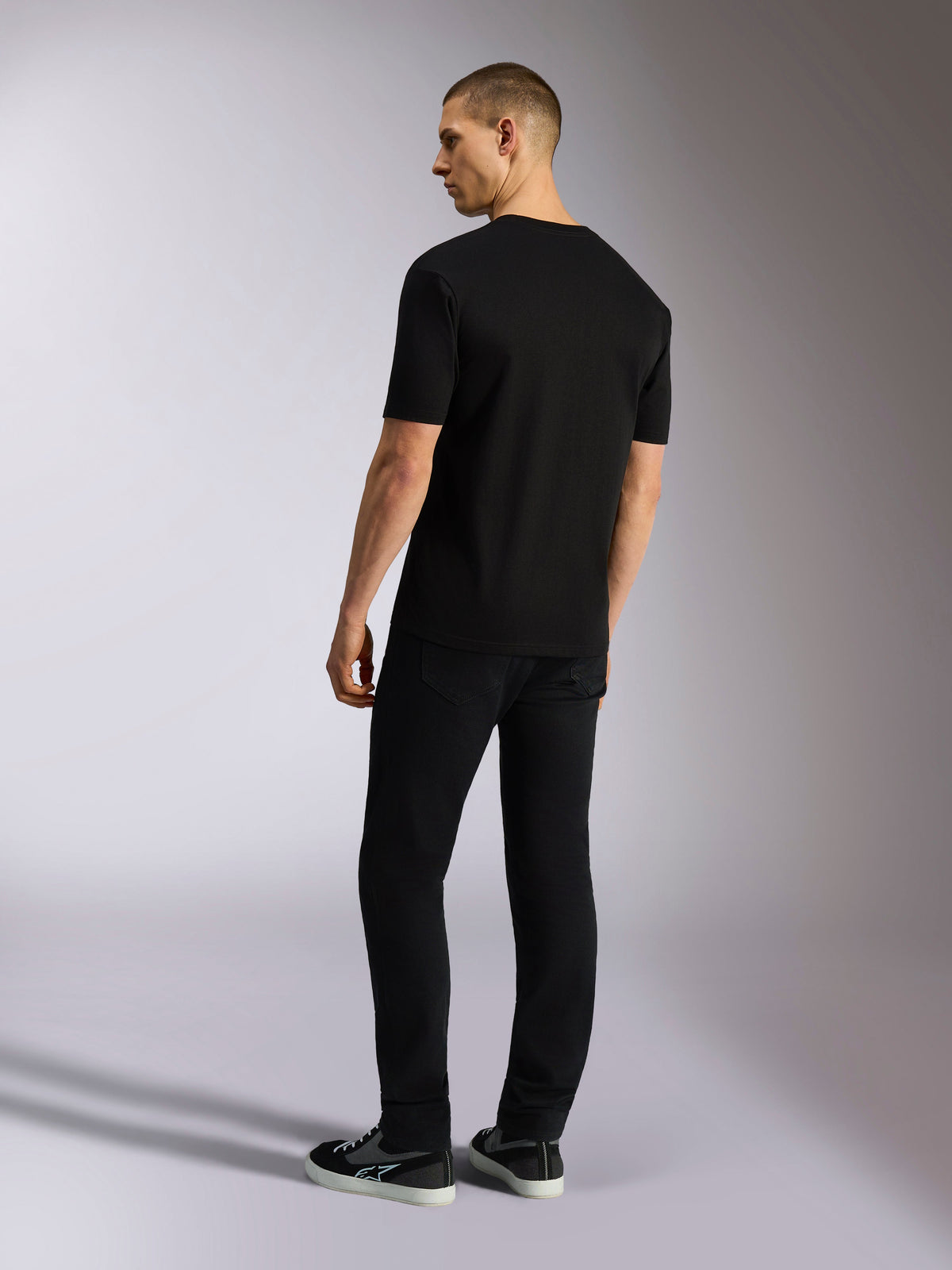 Alpinestars MX CSF Tee, kurzärmeliges T-Shirt, Schwarz, Rückansicht an einem Modell mit schwarzer Hose, lässige Motorsport-Streetwear