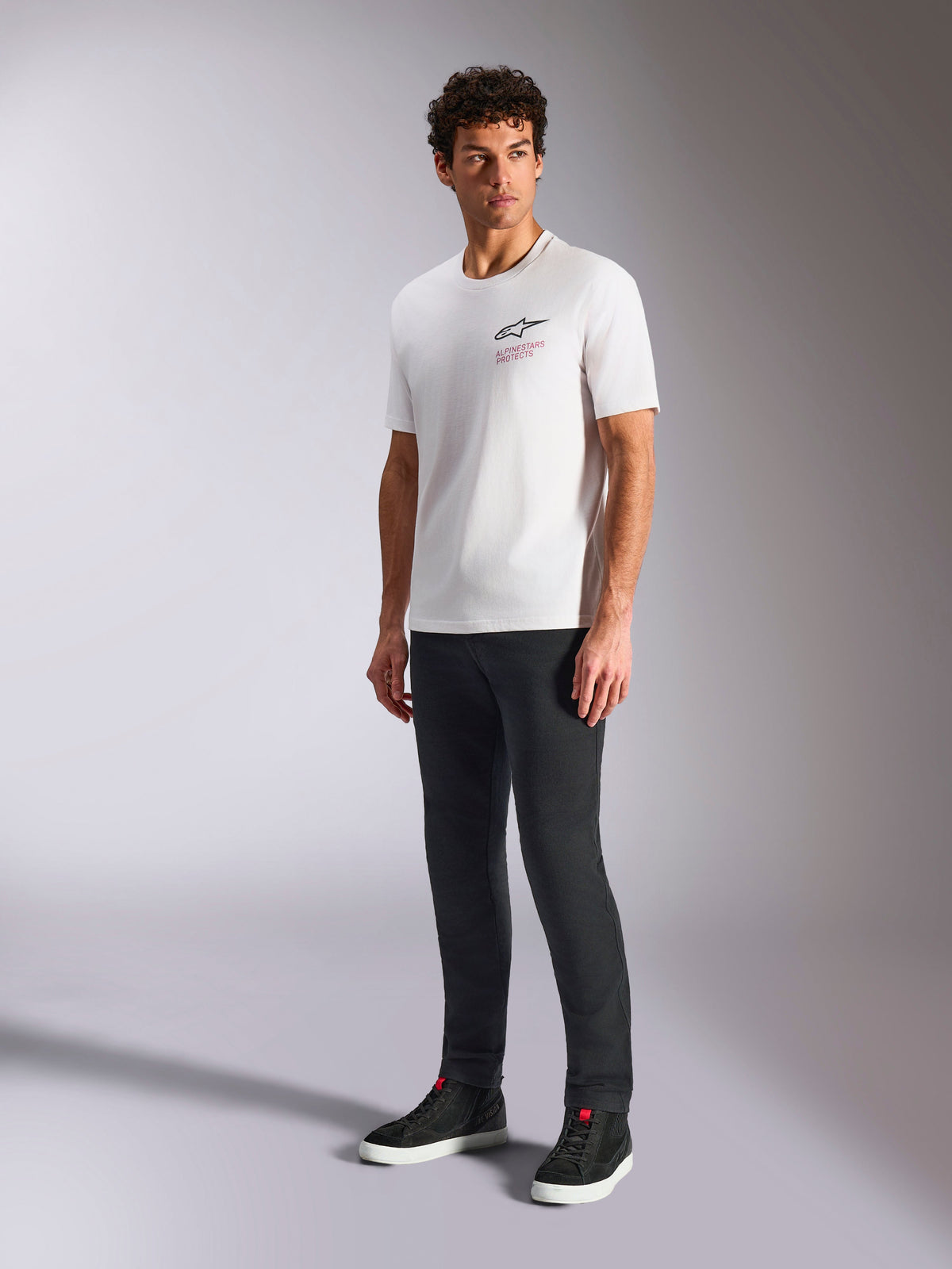 Alpinestars Pop Helmet CSF Tee, Short Sleeve T-Shirt, White, featuring front Astars logo and red text, worn by male model with dark pants and black sneakers, Casual Motorsport Streetwear