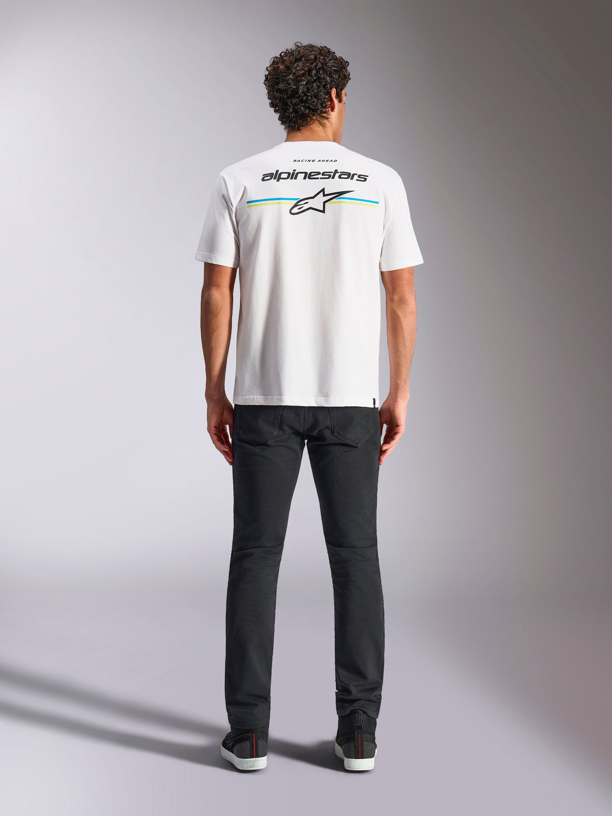 Alpinestars Lanes CSF Tee, Kurzarm-T-Shirt, Weiß, Rückansicht am Model mit Alpinestars-Logo und Astars-Stern über horizontalen blauen und gelben Streifen, lässige Motorsport-Streetwear