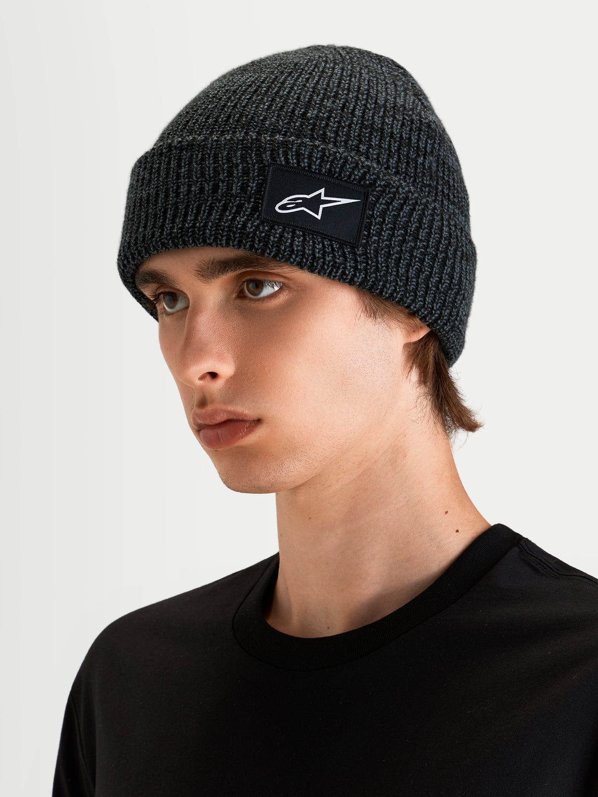 Alpinestars Unload Rib Cuff Beanie, sportswear knit beanie in charcoal melange, worn by a model showcasing the shallow-fit profile and SAstars woven patch logo