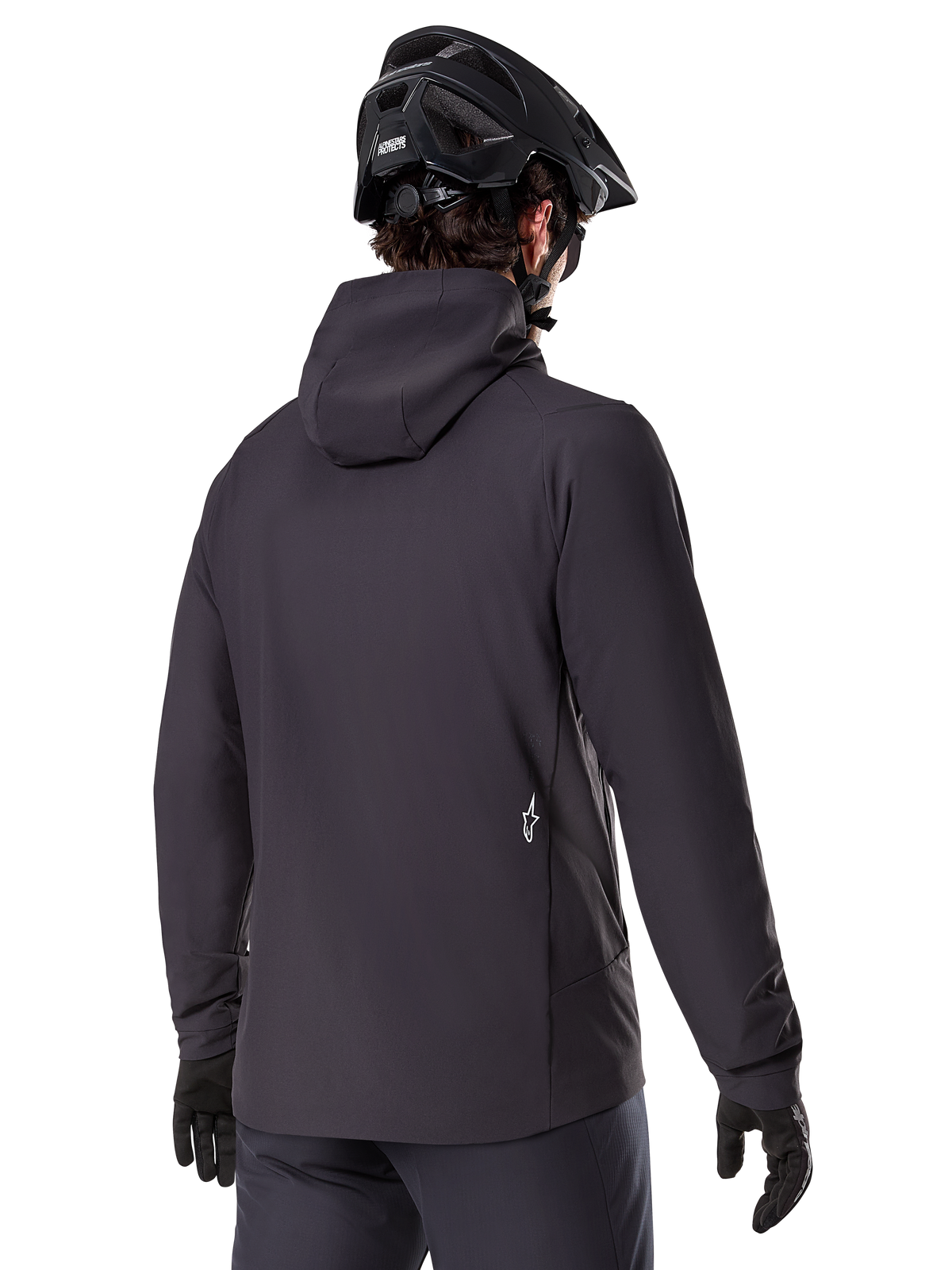 Alpinestars A-Dura Thermojacke, Schwarz, Rückansicht, getragen mit einem schwarzen Mountainbike-Helm und Handschuhen, kleines weißes Astars-Logo auf dem unteren Rücken, leichte isolierte Radjacke