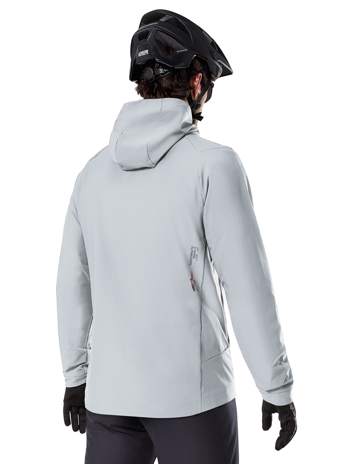 Alpinestars A-Dura Thermojacke, Titanium-Grau, Rückansicht eines Fahrers in der isolierten Kapuzenjacke, kombiniert mit einem schwarzen MTB-Helm und schwarzen Handschuhen, kleines Alpinestars-Logo am unteren Rücken, konzipiert für Mountainbiking bei kaltem Wetter