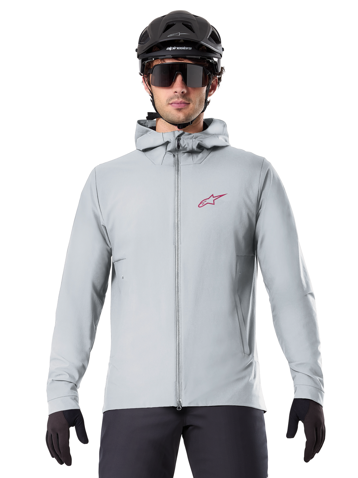 Alpinestars A-Dura Thermal Jacket in Titanium, hellgraue Fahrradjacke mit Kapuze und rotem Stern-Logo auf der Brust, getragen von einem Fahrer mit schwarzem MTB-Helm, Sonnenbrille und Handschuhen, isolierte Ausrüstung fürs Mountainbiken
