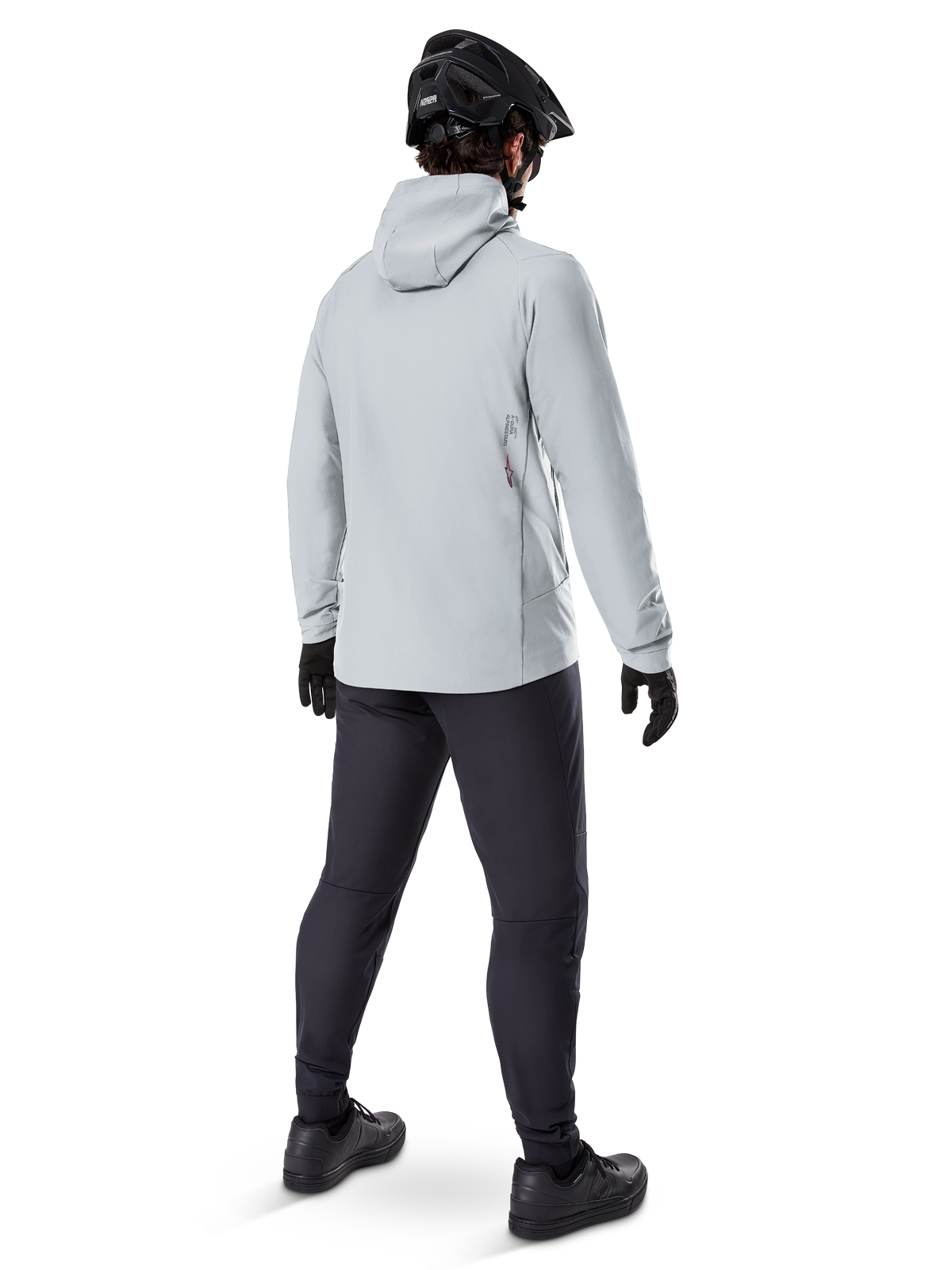 Alpinestars A-Dura Thermojacke in Titanium, Rückansicht eines männlichen Radfahrers in hellgrauer Thermojacke mit Kapuze, kombiniert mit schwarzem MTB-Helm, schwarzen Handschuhen und dunkelgrauer Hose, funktionelle Mountainbike-Ausrüstung