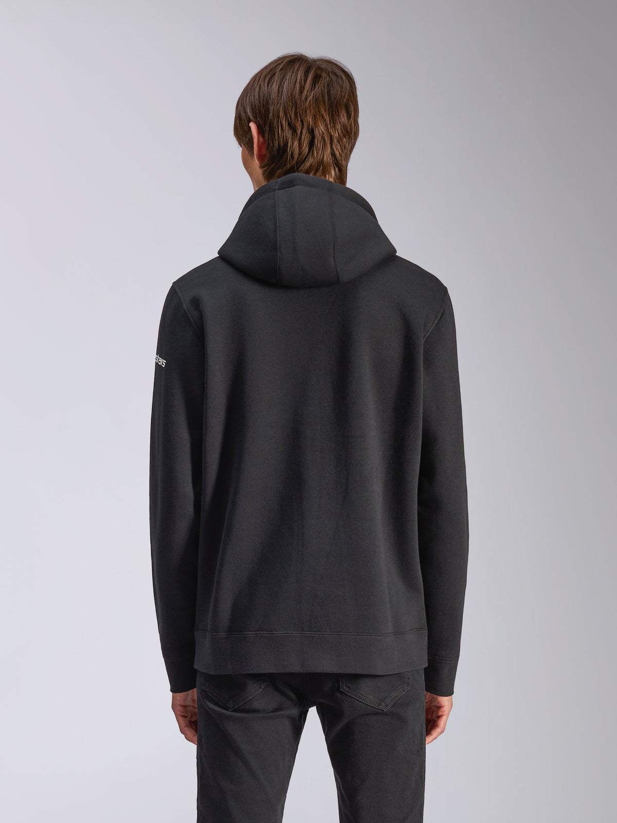Alpinestars Frontal Hoodie, Schwarz, Rückansicht eines lässigen Kapuzenpullovers mit selbstgefütterter Kapuze, geripptem Saum und weißem Wortmarken-Logo am Ärmel, Motorsport-inspirierte Streetwear.
