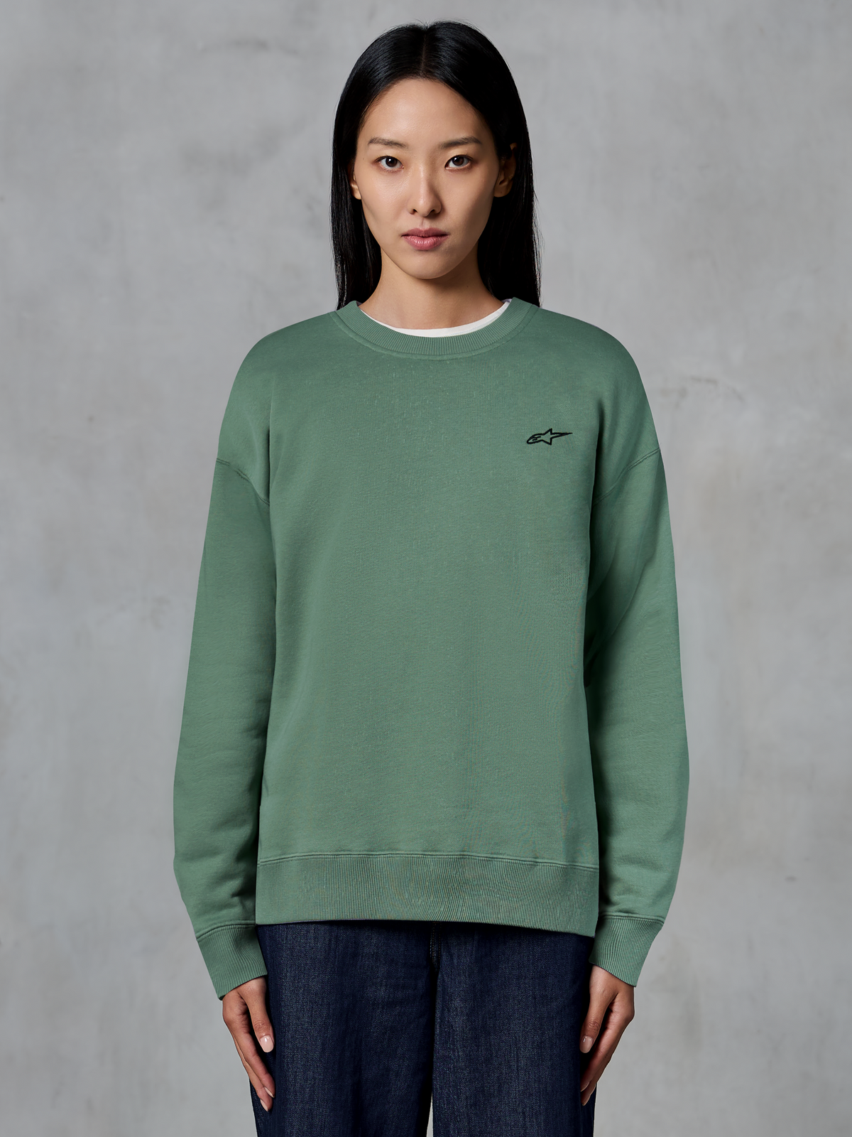 Alpinestars Essentials Ageless Crew, Rundhals-Sweatshirt, Kaktusgrün, von einem Model getragen, kleines schwarzes Logo auf der Brust, gerippter Kragen, Bündchen und Saum, lässige Motorsport-Streetwear
