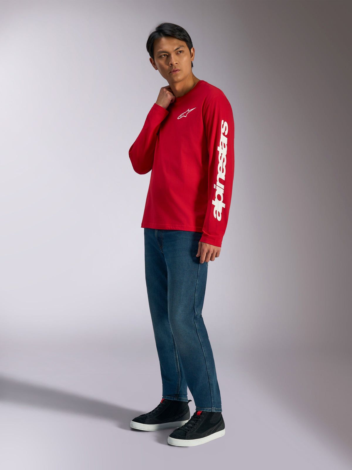 Alpinestars Trackside CSF Long Sleeve Tee, Red with white Alpinestars branding on chest and sleeve, worn by model with blue jeans and black sneakers, casual motorsport-inspired streetwear