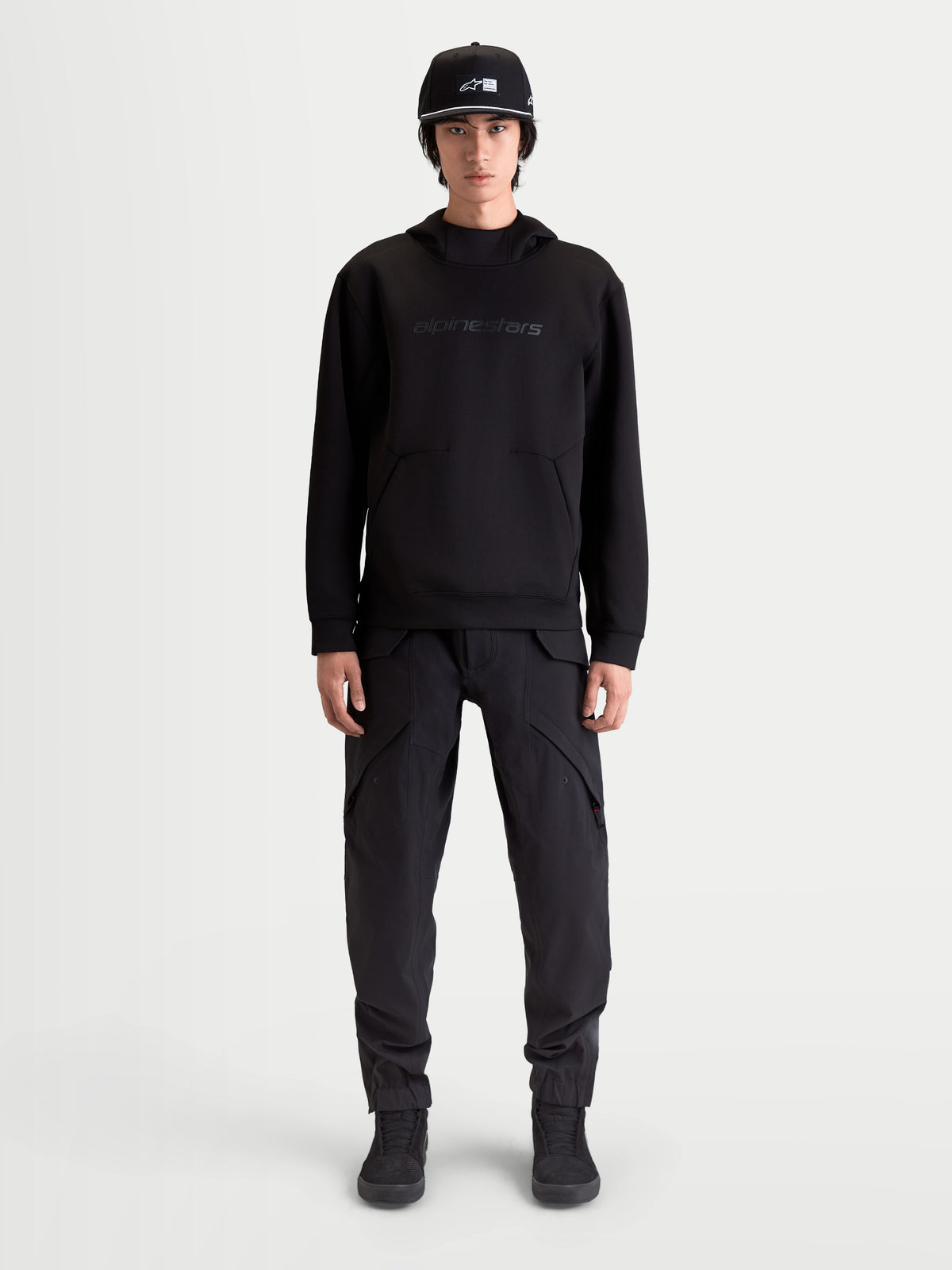 Alpinestars Datrix Hoodie, Herren Sportswear-Kapuzenpullover, Schwarz, mit tonalem HD-Branding, Tri-Blend-Doppelfleece und Tasche mit Abnäherdetail, am Modell präsentiert für einen motorsport-inspirierten Alltagsstil.