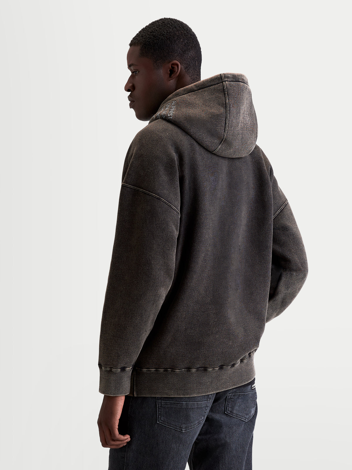 Alpinestars Infinite Washed Oversized Hoodie, Herren-Sportswear-Pullover in Schwarz mit Snow-Wash-Finish, Fleece, lockere Oversized-Passform mit gesticktem Logo-Detail auf der Kapuze, Rückansicht am Modell.