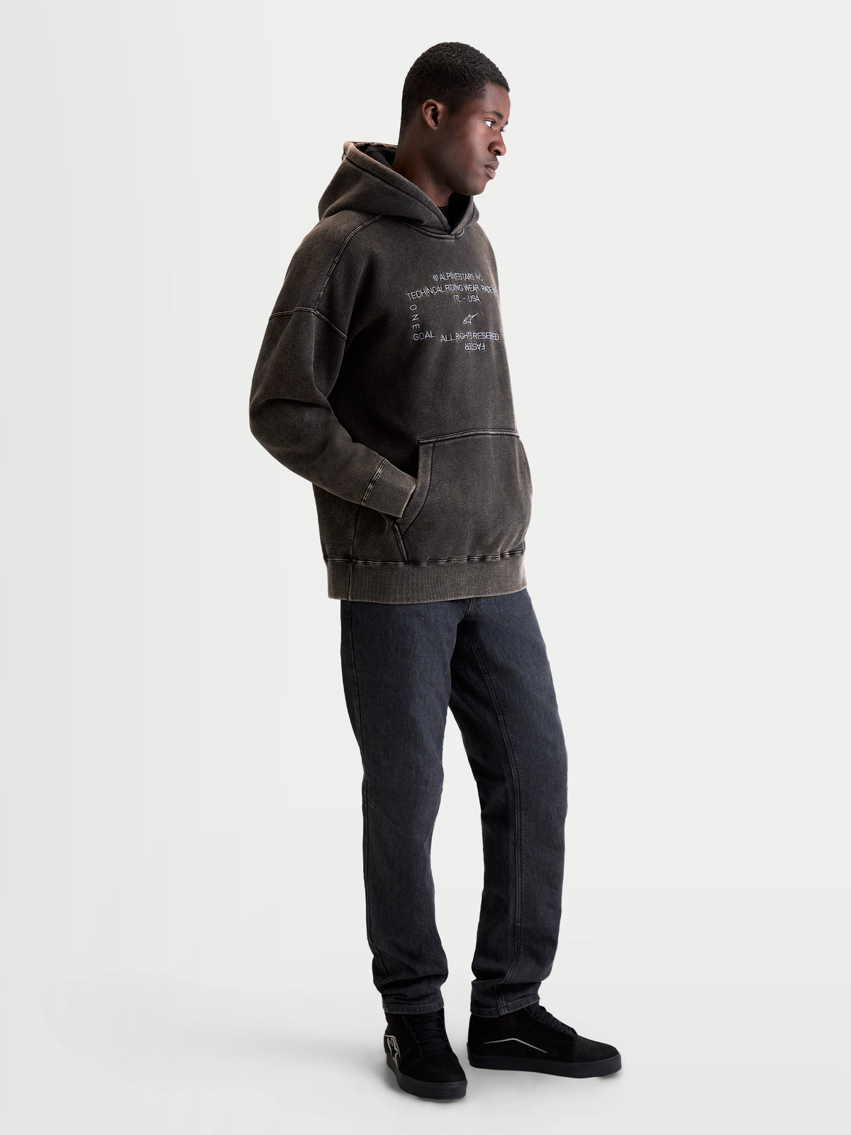 Alpinestars Infinite Washed Oversized Hoodie, Sportswear-Kapuzenpullover für Herren, Schwarz mit Snow-Wash-Finish, weißes gesticktes Logo auf der Brust, Kängurutasche, lässige Oversized-Passform auf Model.