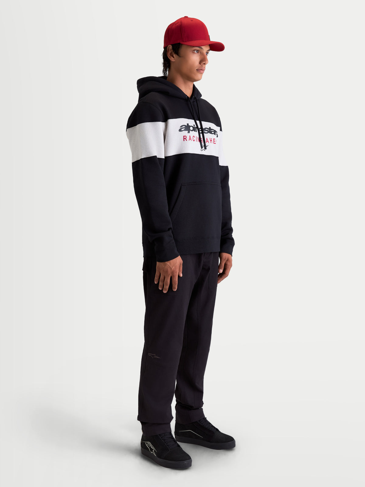 Alpinestars Cubic Hoodie, Herren Sportswear Kapuzenpullover, Schwarz und Weiß, Color-Block-Design mit Alpinestars-Wortlogo auf der Brust, weiches Fleece-Gewebe aus Baumwollmischung, Lifestyle-Ansicht am Modell.
