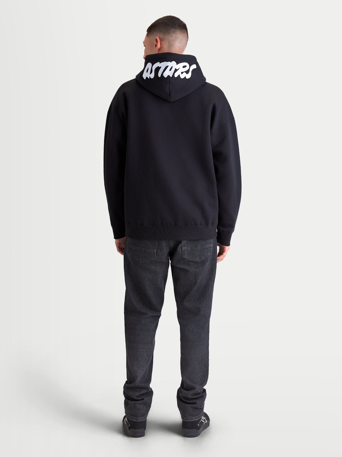 Alpinestars Pioneer Oversized Hoodie, Sportswear-Fleecejacke mit Reißverschluss in Schwarz, Rückansicht mit weißer Astars-Stickerei auf der Kapuze, Oversized-Passform, bequemes Baumwollmischgewebe für den Alltag.