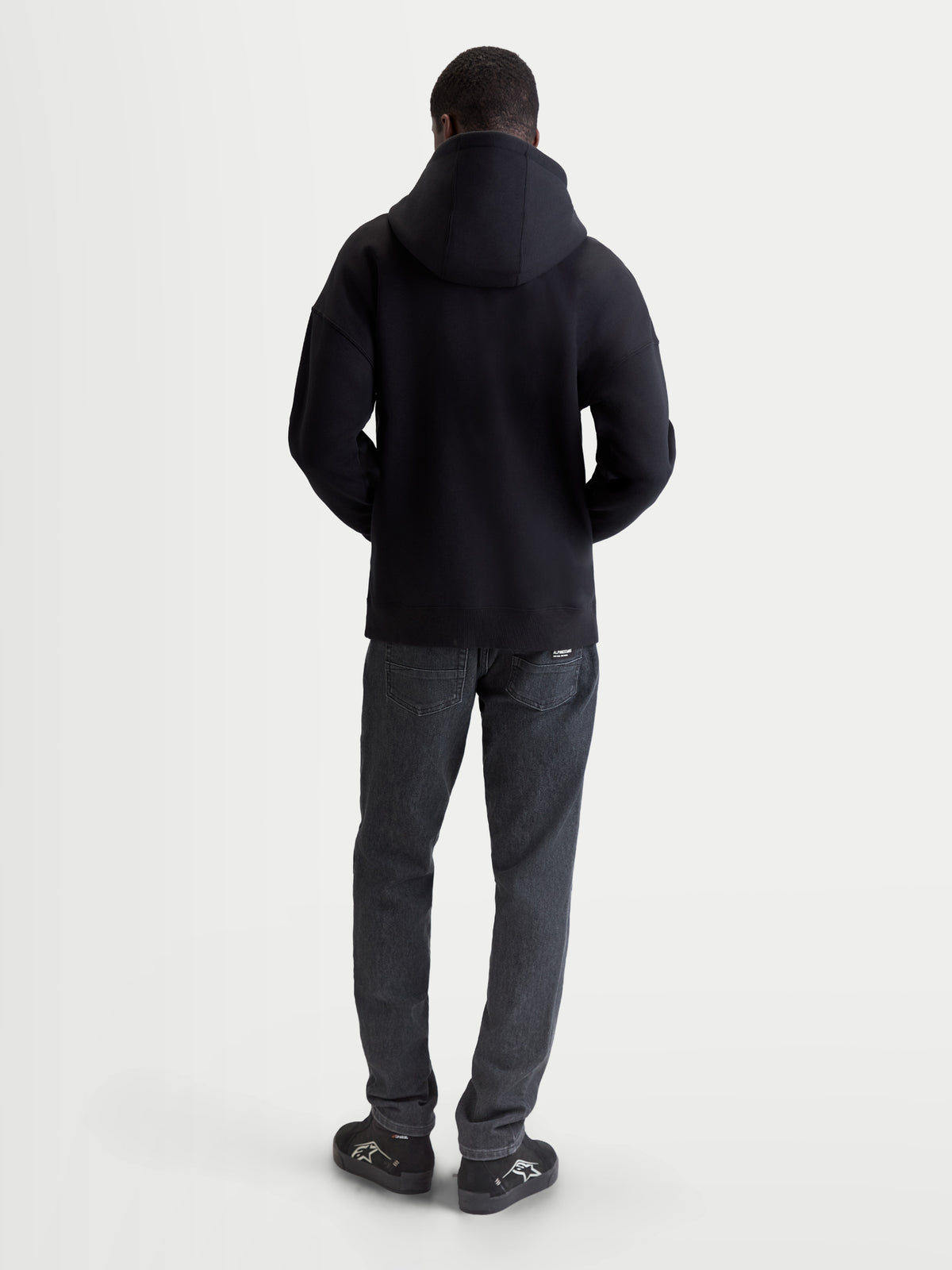 Alpinestars Entity Oversized Hoodie, Herren-Sportswear Zip-Fleecejacke in Schwarz, Rückansicht am Model, entspannte Oversized-Passform, Baumwoll- und Recycling-Polyester-Mischgewebe, lässige Motorsport-Bekleidung.