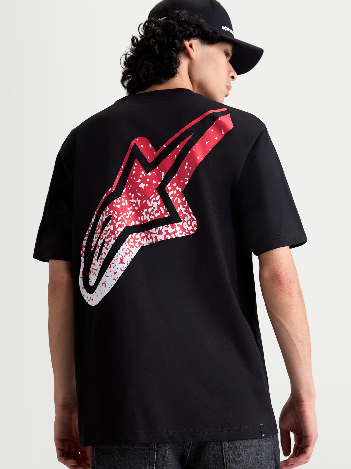 Alpinestars Meteor CSF T-Shirt, Kurzarm-Sportswear-T-Shirt in Schwarz, Rückansicht am Model mit großer rot-weißer Astars-Logo-Grafik im MX-Stil, lässige Motorsport-Bekleidung.
