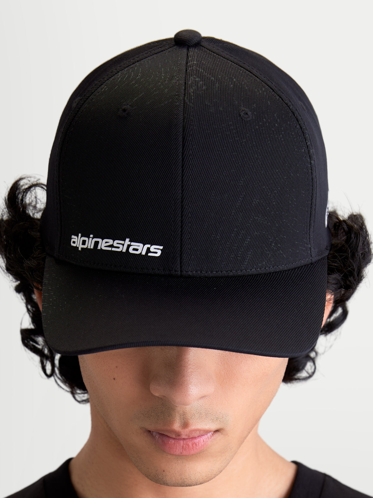 Alpinestars Points Kappe, schwarze Sportswear-Kappe mit gebogenem Schirm, weißes Alpinestars-Wortlogo auf der Vorderseite, leichte Nylon-Tactel-Konstruktion, am Modell getragen.