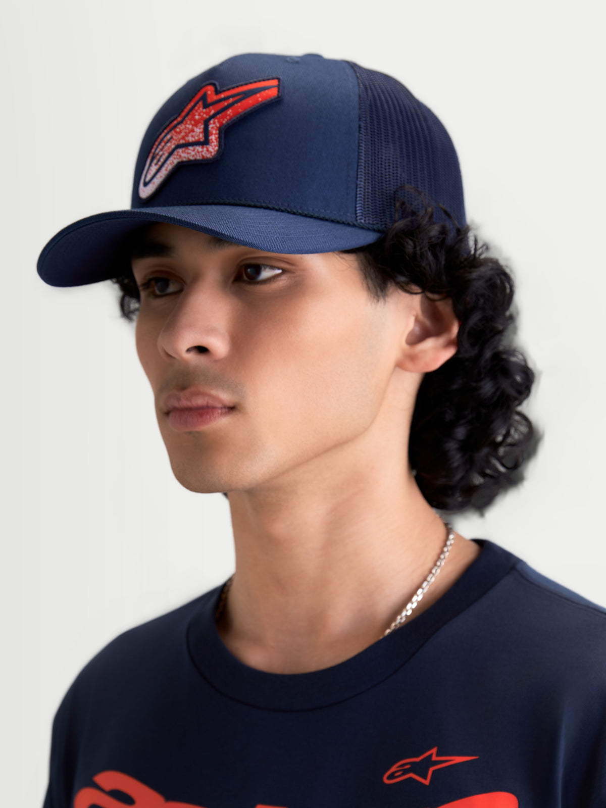 Alpinestars Meteorite Trucker-Kappe, Sportswear Mesh-Kappe in Navy-Blau mit rotem Astars Gravel-Texture-Logo, gebogener Schirm und strukturierte Krone, Ansicht am Modell.