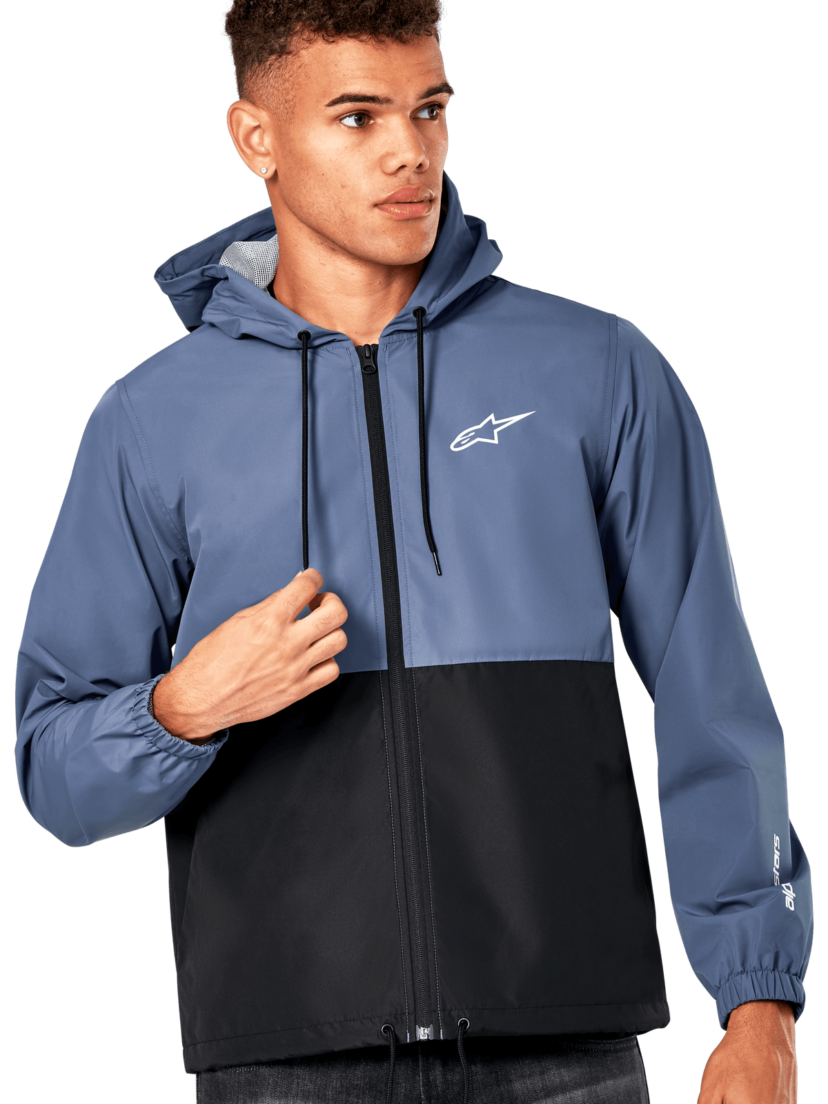 Männliches Model trägt die Alpinestars Speeder Windbreaker-Jacke, Farbblock-Design in Schieferblau und Schwarz, Kapuze mit schwarzen Kordelzügen, weißes Logo auf der Brust, lässiger, vom Motorsport inspirierter Windbreaker