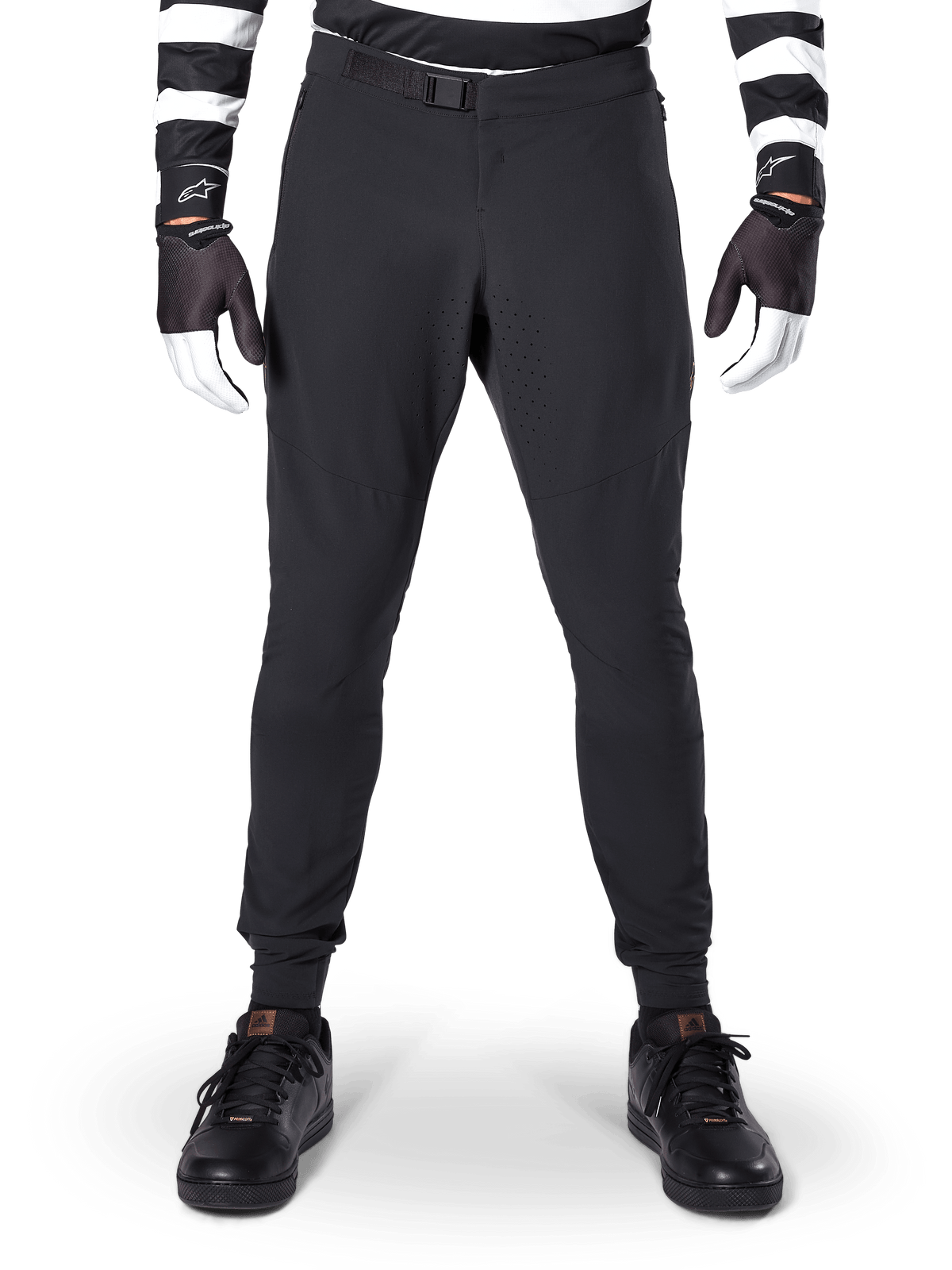 Alpinestars A-Aria Elite Hose, Mountainbike-Hose, Schwarz, Vorderansicht mit Laserperforationen und Magnet-Schnallenverschluss, kombiniert mit schwarz-weiß gestreiftem Trikot und schwarzen Handschuhen, Performance-Radbekleidung für Trail-Fahrten