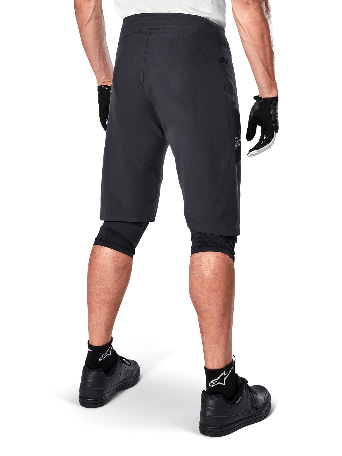 Alpinestars A-Aria Shorts, Mountainbike-Shorts, Schwarz, Rückansicht zeigt Performance-Passform und klares Design, getragen mit schwarzen Handschuhen und Socken mit weißem Astars-Logo, technische Radsportbekleidung für Offroad-Fahrten