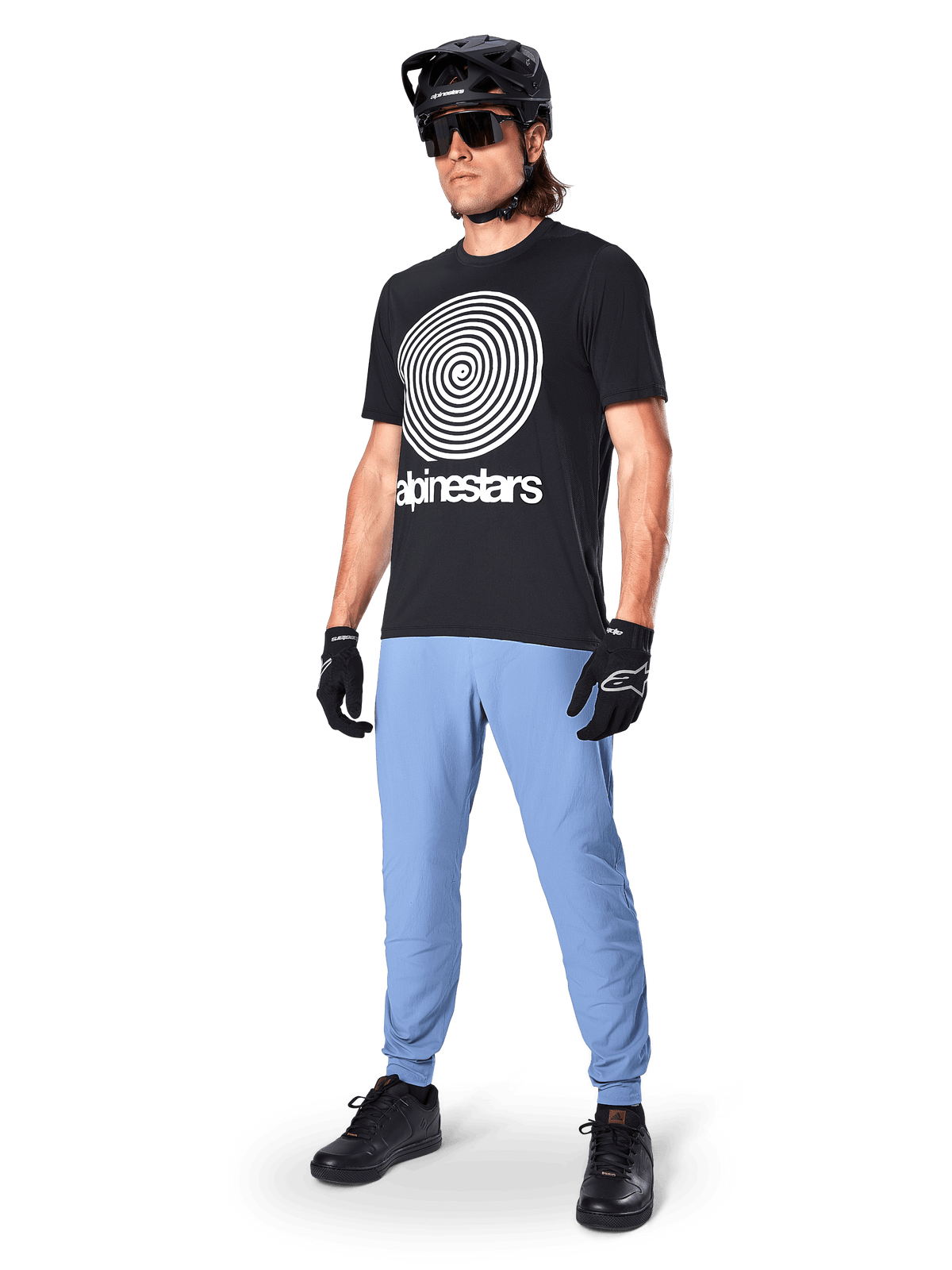 Alpinestars A-Dura Hose, MTB-Hose, Infinity Blue, getragen mit schwarzem Grafik-T-Shirt mit weißem Spiral-Logo, schwarzem Helm, Sonnenbrille und schwarzen Handschuhen, professionelle Mountainbike-Ausrüstung