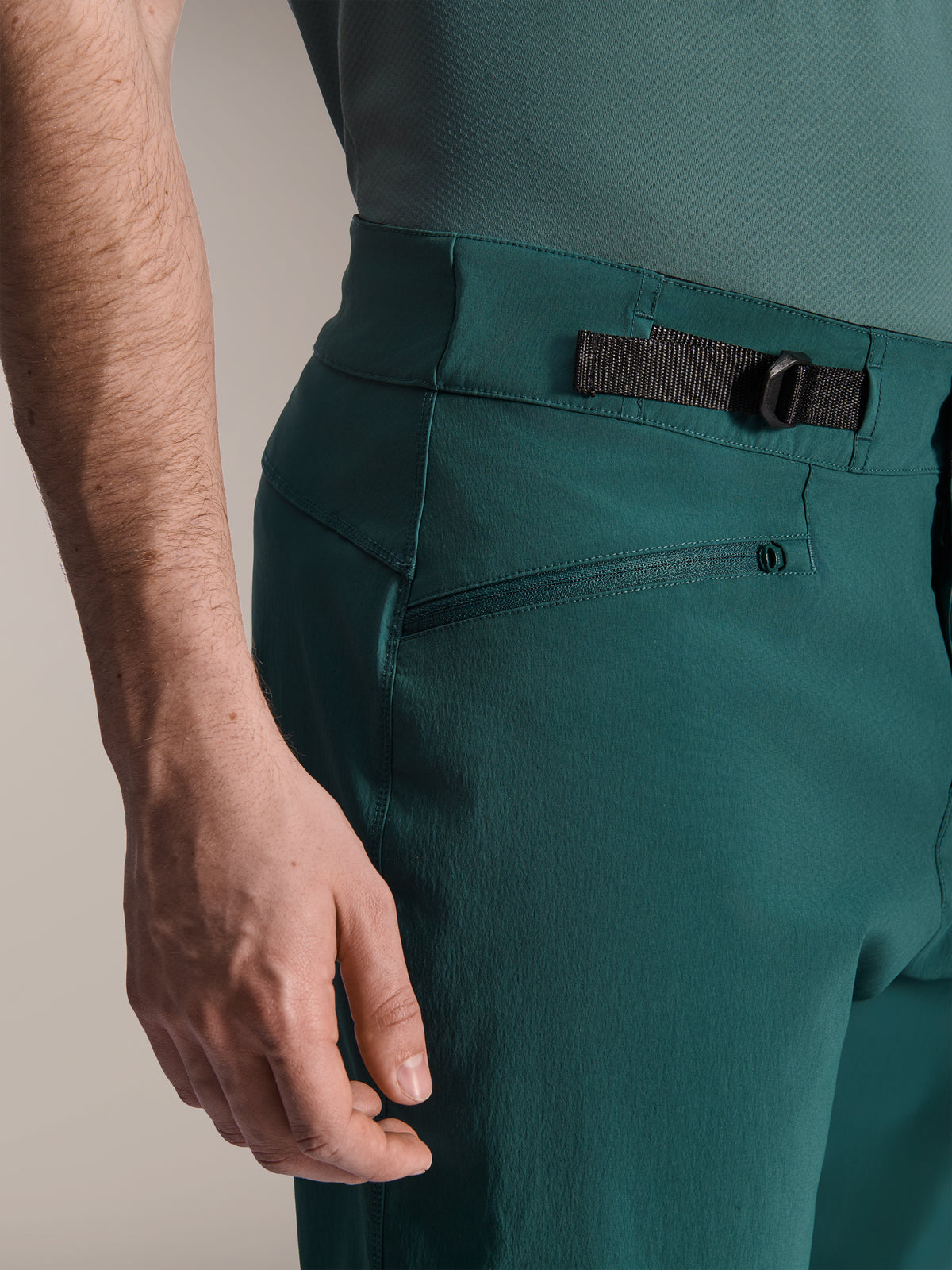Alpinestars A-Dura Shorts, Dark Pine Green, Nahaufnahme des verstellbaren seitlichen Taillenverstellers und der Reißverschlusstasche, strapazierfähige Performance-Ausrüstung für Mountainbiking.