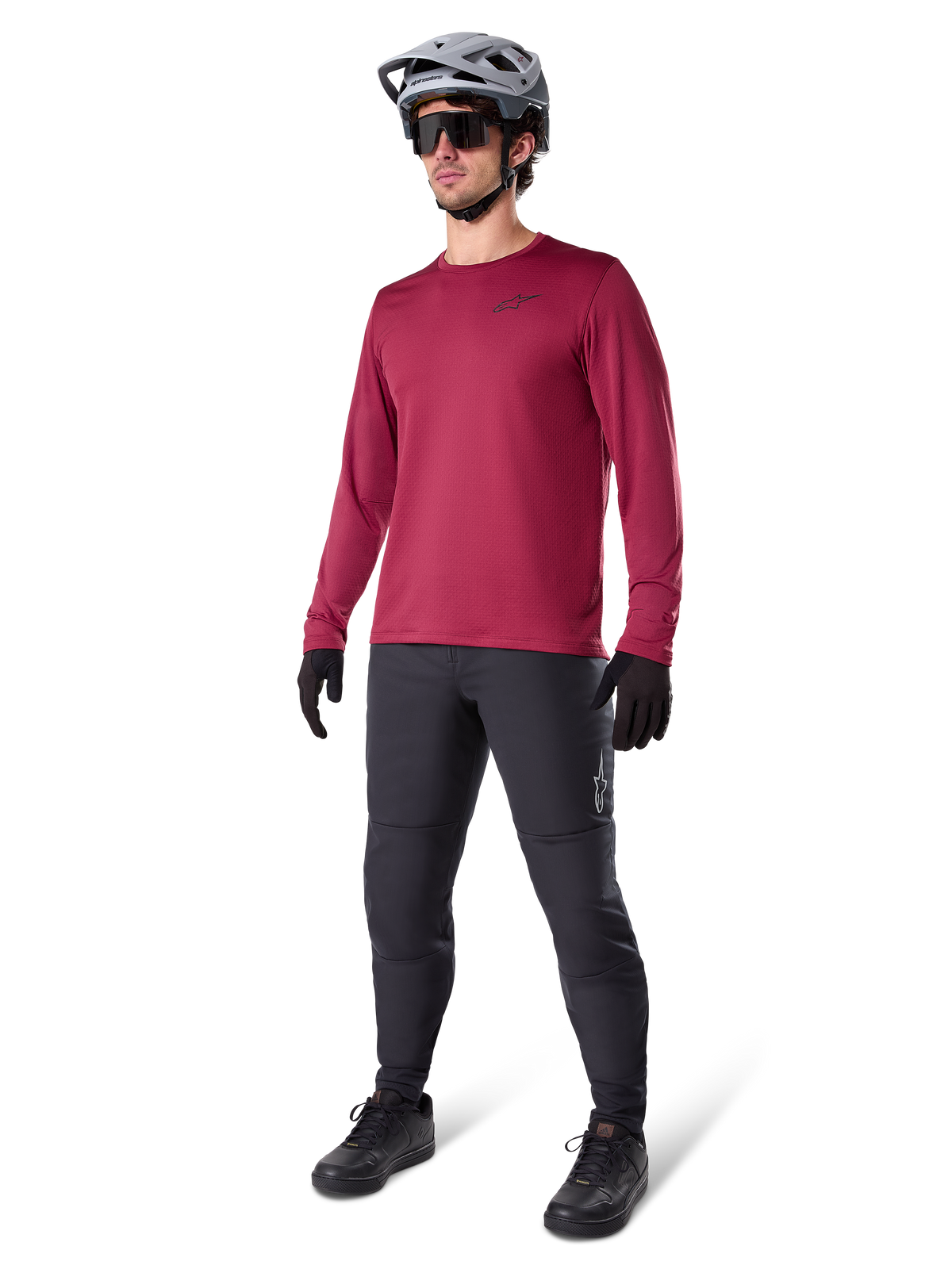 Alpinestars A-Dura Thermal Jersey in Burgundy, langärmliges, isoliertes Radsport-Oberteil getragen mit dunkelgrauer Mountainbike-Hose, schwarzen Handschuhen und einem grauen Helm, Ganzkörper-Studioaufnahme von Kaltwetter-MTB-Ausrüstung.