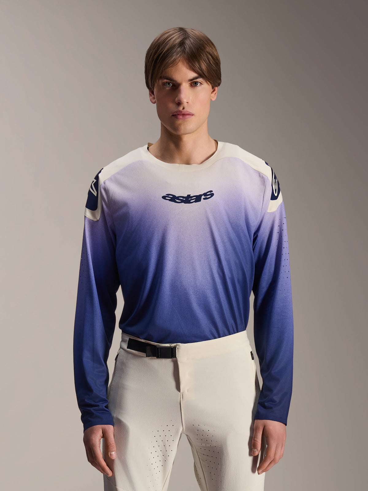 Alpinestars A-Aria Polartec Maker Elite Trikot, Langarm-MTB-Trikot, Baja Blue mit weiß-blauem Farbverlauf, von einem Model mit weißer Hose getragen, mit dunkelblauem Logo auf der Brust und Laserperforationen an den Ärmeln, Performance-Mountainbike-Bekleidung