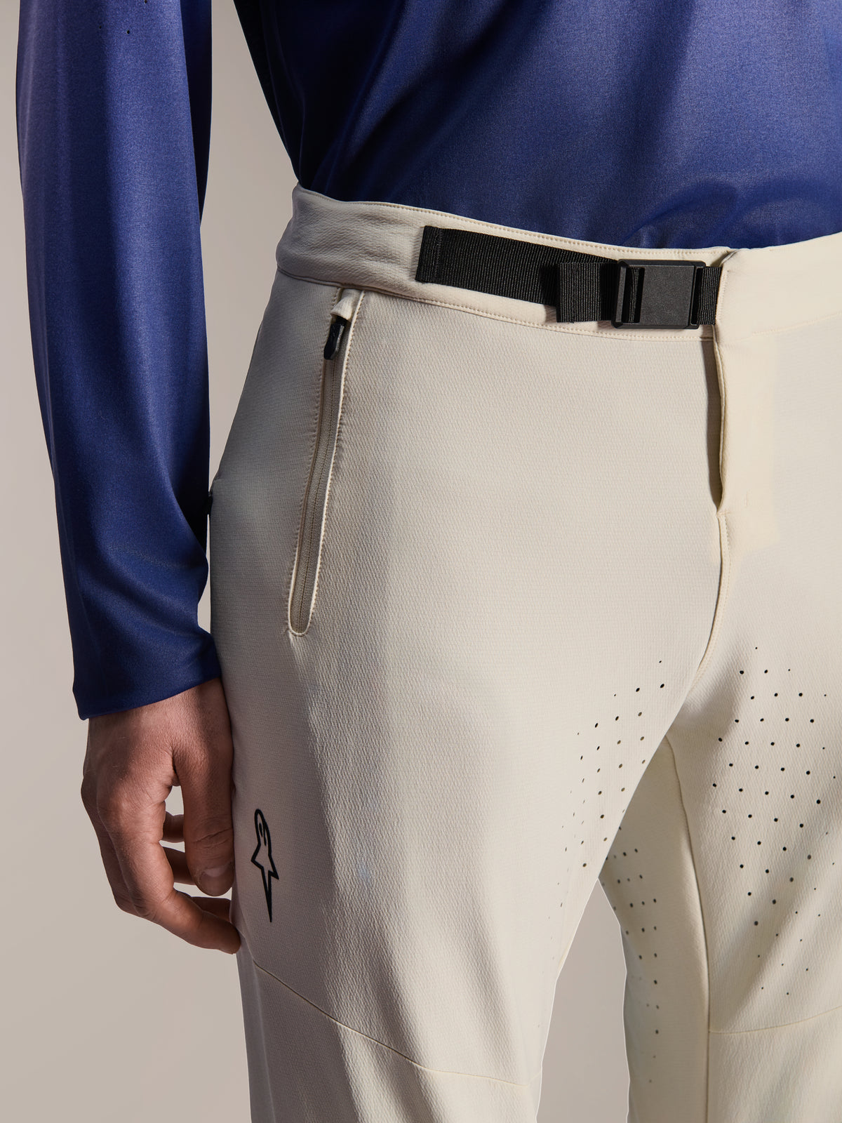 Alpinestars A-Aria Elite Hose, Mountainbike-Hose, Ecru, Nahaufnahme mit einem schwarzen Magnetverschluss am Bund, Reißverschlusstasche und lasergeschnittenen Belüftungslöchern, Performance-Offroad-Fahrradausrüstung.