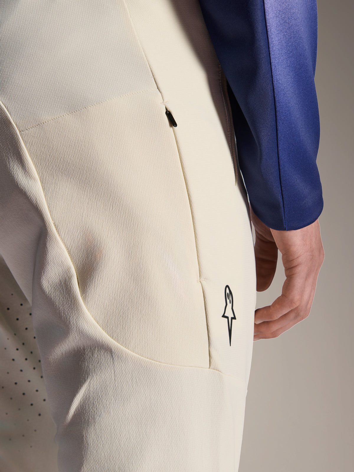 Alpinestars A-Aria Elite Hose, Performance-Hose in Ecru Off-White, Nahaufnahme der seitlichen Reißverschlusstasche und Laserperforationen zur Belüftung, minimalistisches Logo-Detail, hochelastisches Material für Mountainbiking
