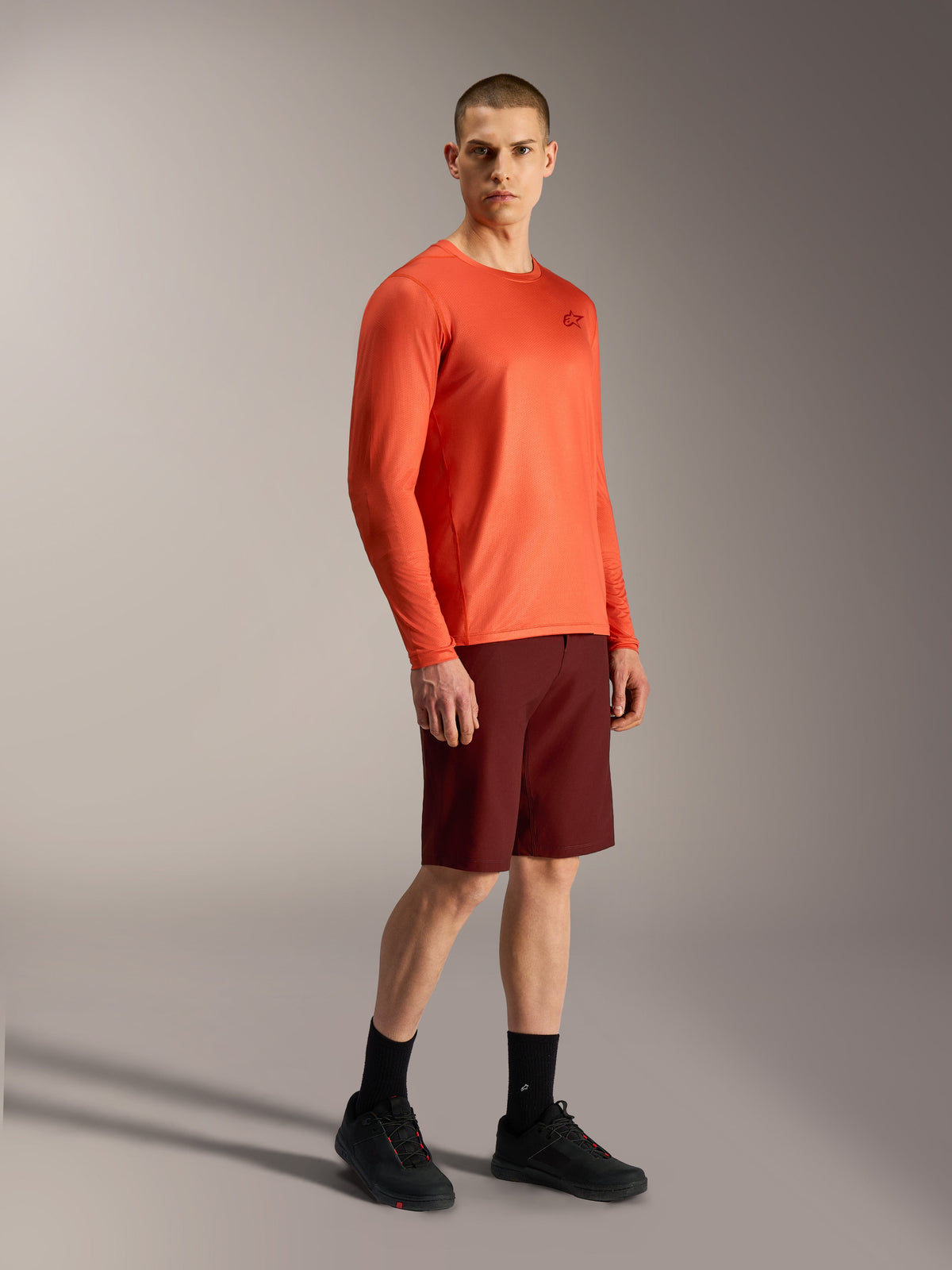 Alpinestars A-Dura Air orange long-sleeve jersey and bordeaux A-Dura Ride shorts, professional MTB performance gear.