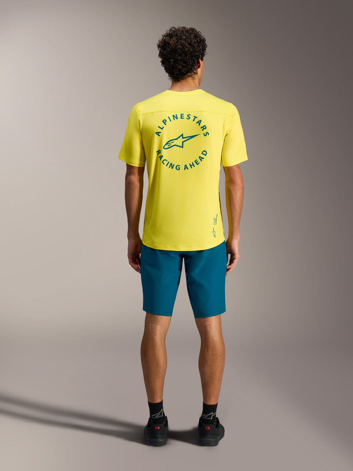 Gelbes A-Dura Air SS Trikot mit blaugrünem Rückenlogo und A-Dura Ride Shorts, professionelle MTB-Bekleidung.