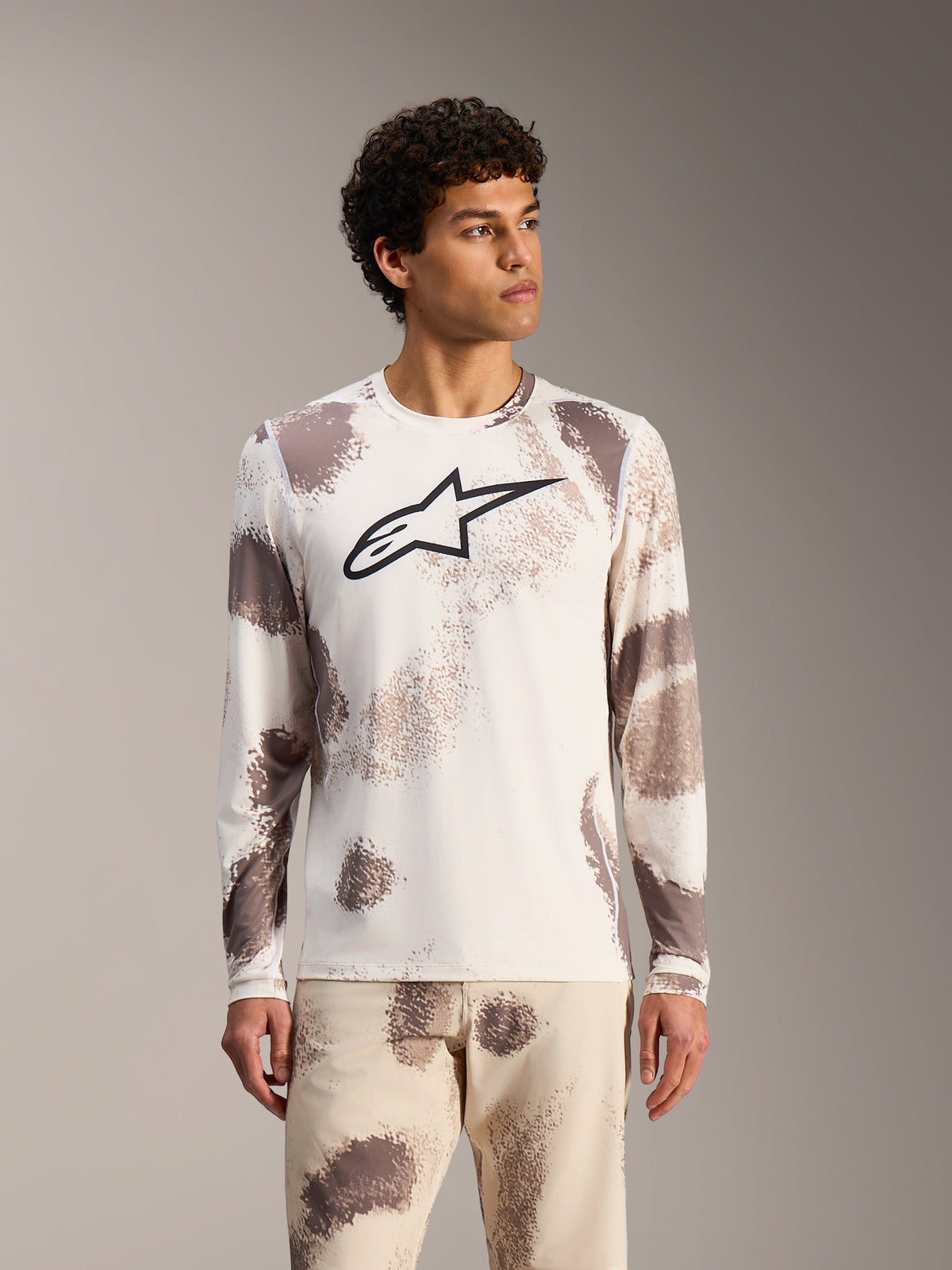 Alpinestars A-Dura Ride Langarmtrikot in Sand Camo, weißes MTB-Top mit abstrakten Mustern und schwarzem Brust-Logo.