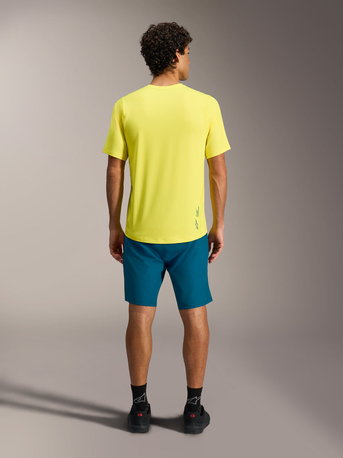 Gelbes A-Dura Ride SS Jersey und blaugrüne A-Dura Ride Shorts in der Rückansicht, funktionale MTB-Bekleidung.