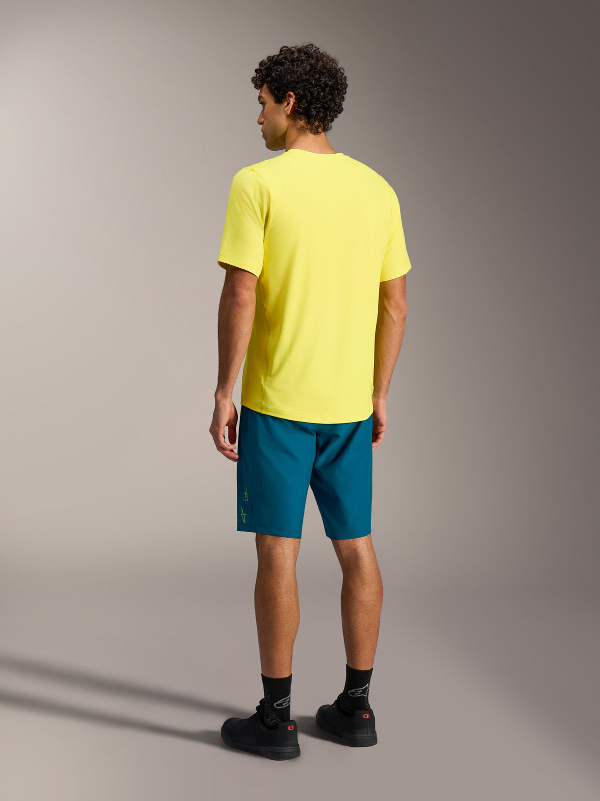 Gelbes A-Dura Ride SS Trikot und blaugrüne A-Dura Ride Shorts, Alpinestars MTB-Bekleidung in der Rückansicht.